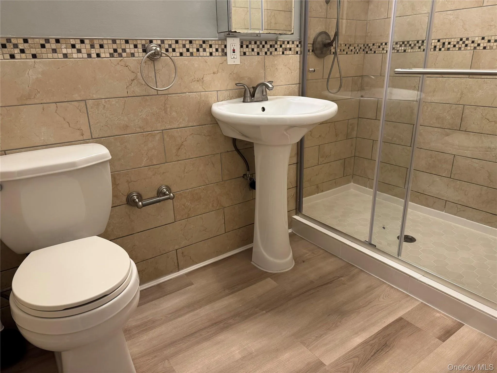 Bathroom with an enclosed shower, hardwood / wood-style floors, toilet, and tile walls Bathroom with an enclosed shower, hardwood / wood-style floors, toilet, and tile walls