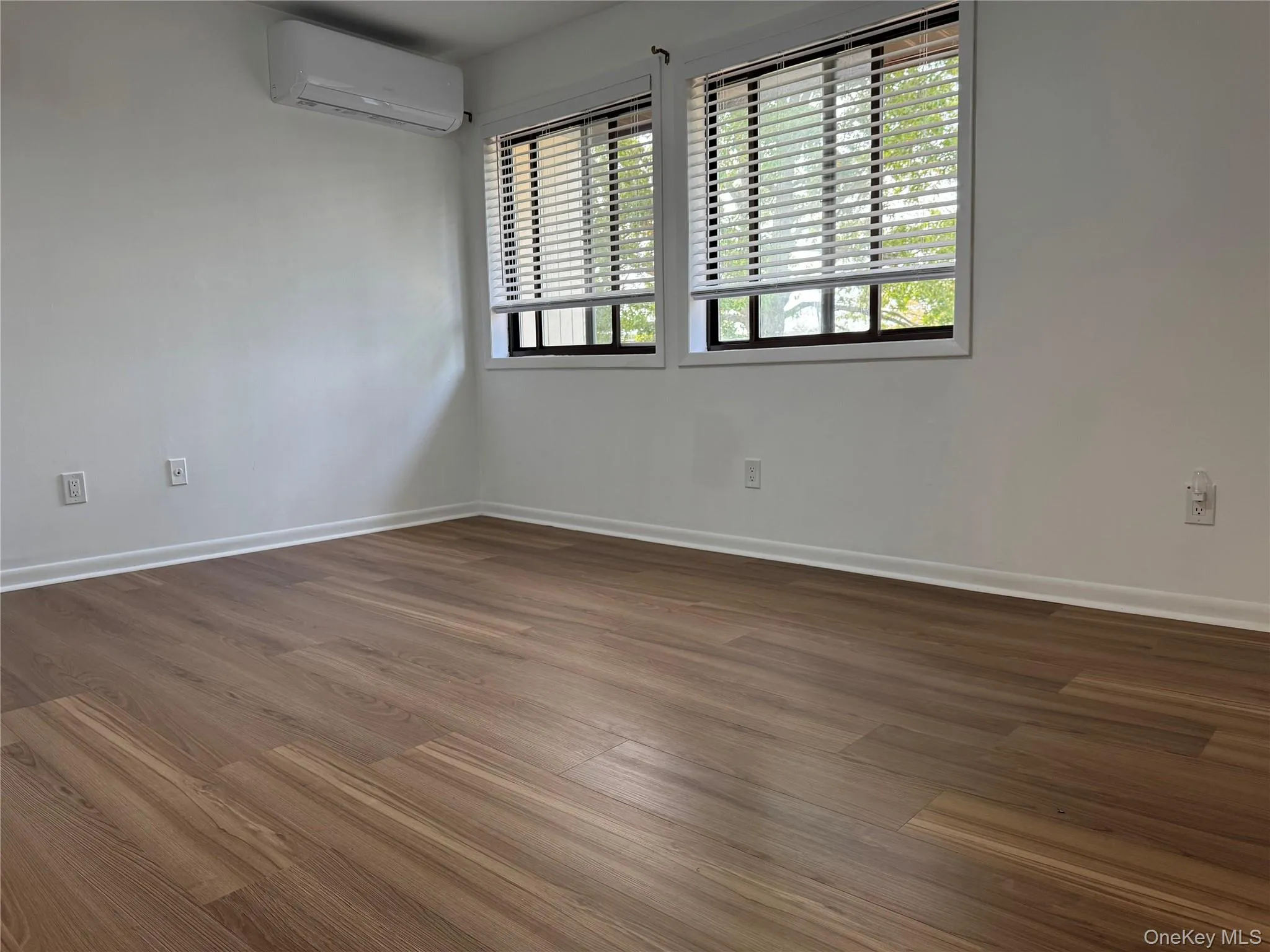 Spare room with wood finished floors and an AC wall unit Spare room with wood finished floors and an AC wall unit