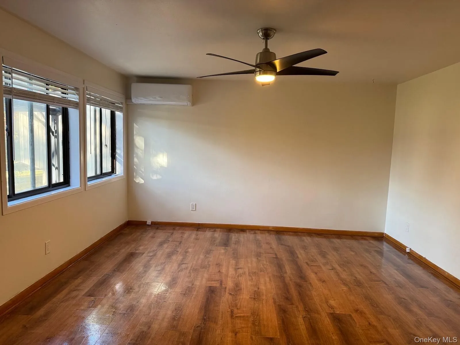 Unfurnished room with dark wood-type flooring, a ceiling fan, and a wall mounted air conditioner Unfurnished room with dark wood-type flooring, a ceiling fan, and a wall mounted air conditioner