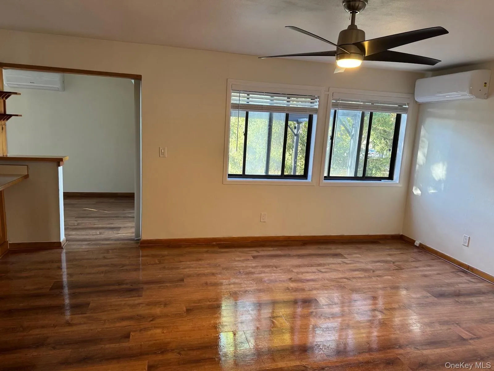 Unfurnished room with wood finished floors, a ceiling fan, and an AC wall unit Unfurnished room with wood finished floors, a ceiling fan, and an AC wall unit