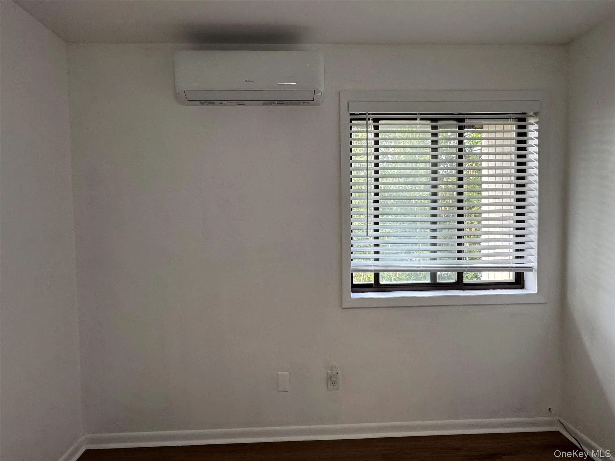 Unfurnished room with dark wood-style flooring and a wall unit AC Unfurnished room with dark wood-style flooring and a wall unit AC