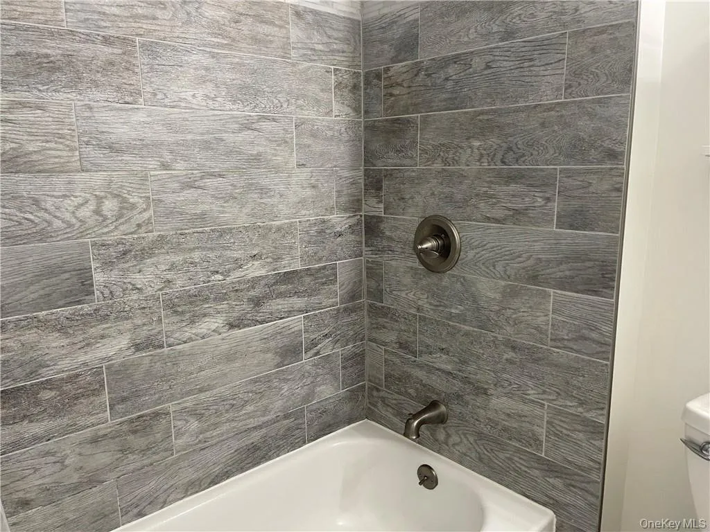 Bathroom featuring tiled shower / bath and toilet Bathroom featuring tiled shower / bath and toilet