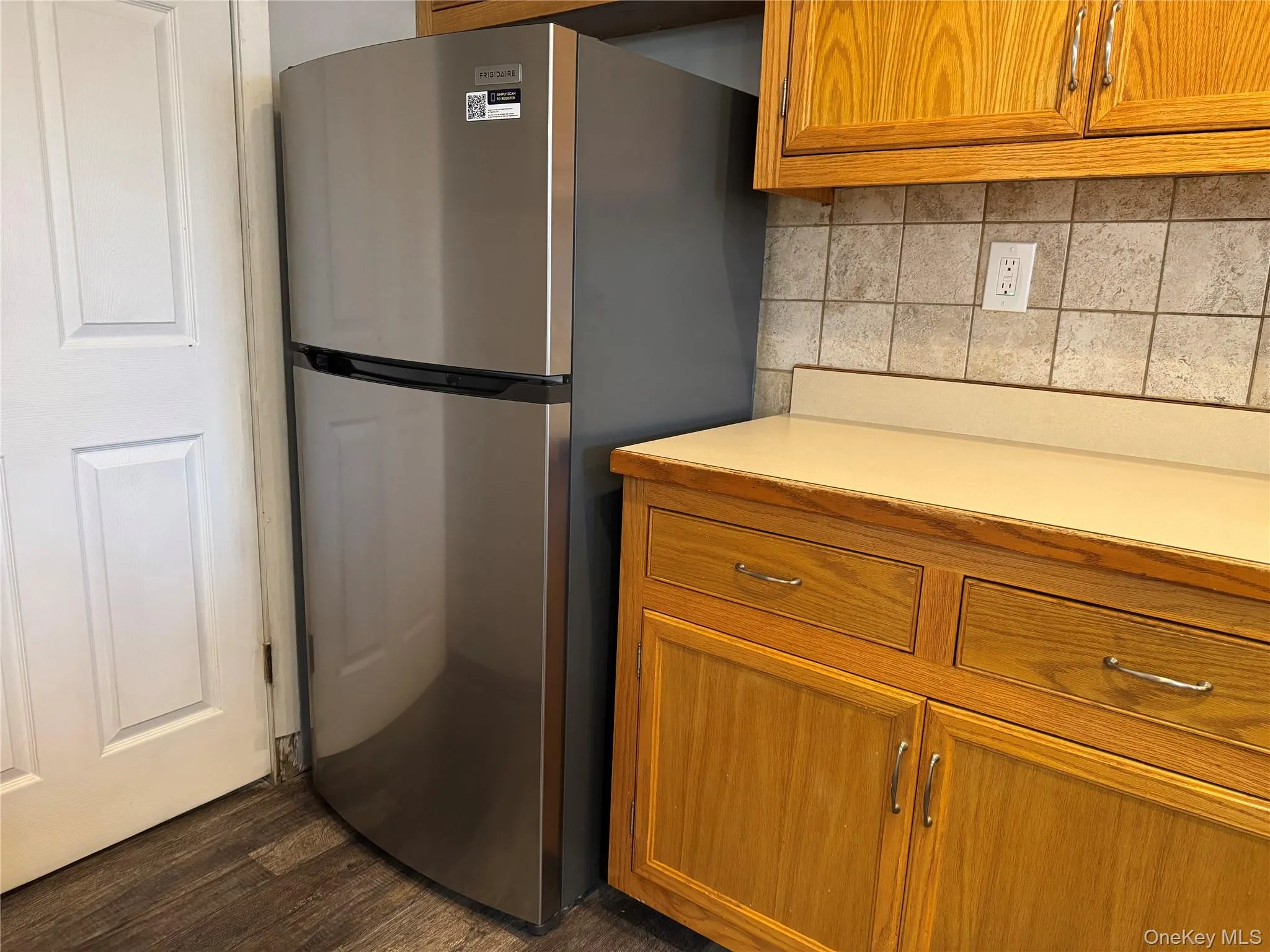 Kitchen with dark hardwood / wood-style floors, stainless steel refrigerator, and tasteful backsplash Kitchen with dark hardwood / wood-style floors, stainless steel refrigerator, and tasteful backsplash