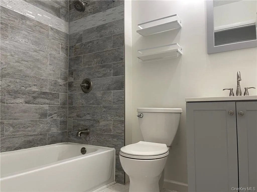 Full bathroom featuring tiled shower / bath, vanity, and toilet Full bathroom featuring tiled shower / bath, vanity, and toilet