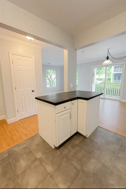 Kitchen featuring white cabinetry, dark countertops, ornamental molding, and light wood-type flooring Kitchen featuring white cabinetry, dark countertops, ornamental molding, and light wood-type flooring