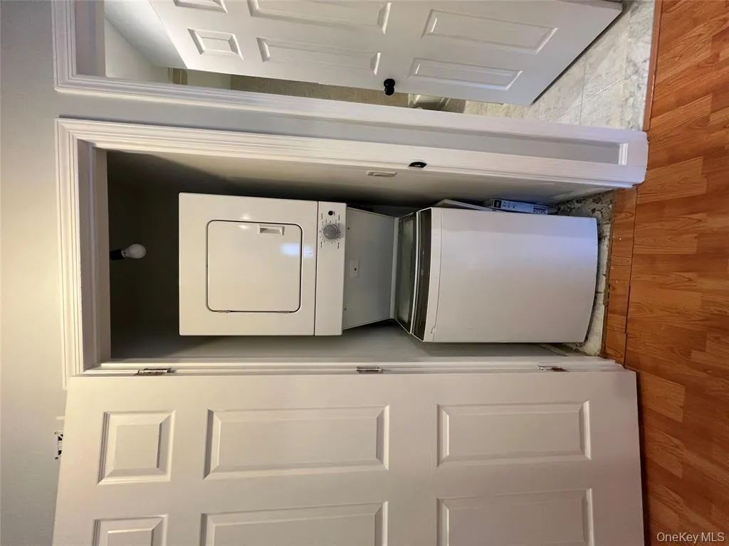 Washroom with light wood-style floors and stacked washing machine and dryer Washroom with light wood-style floors and stacked washing machine and dryer