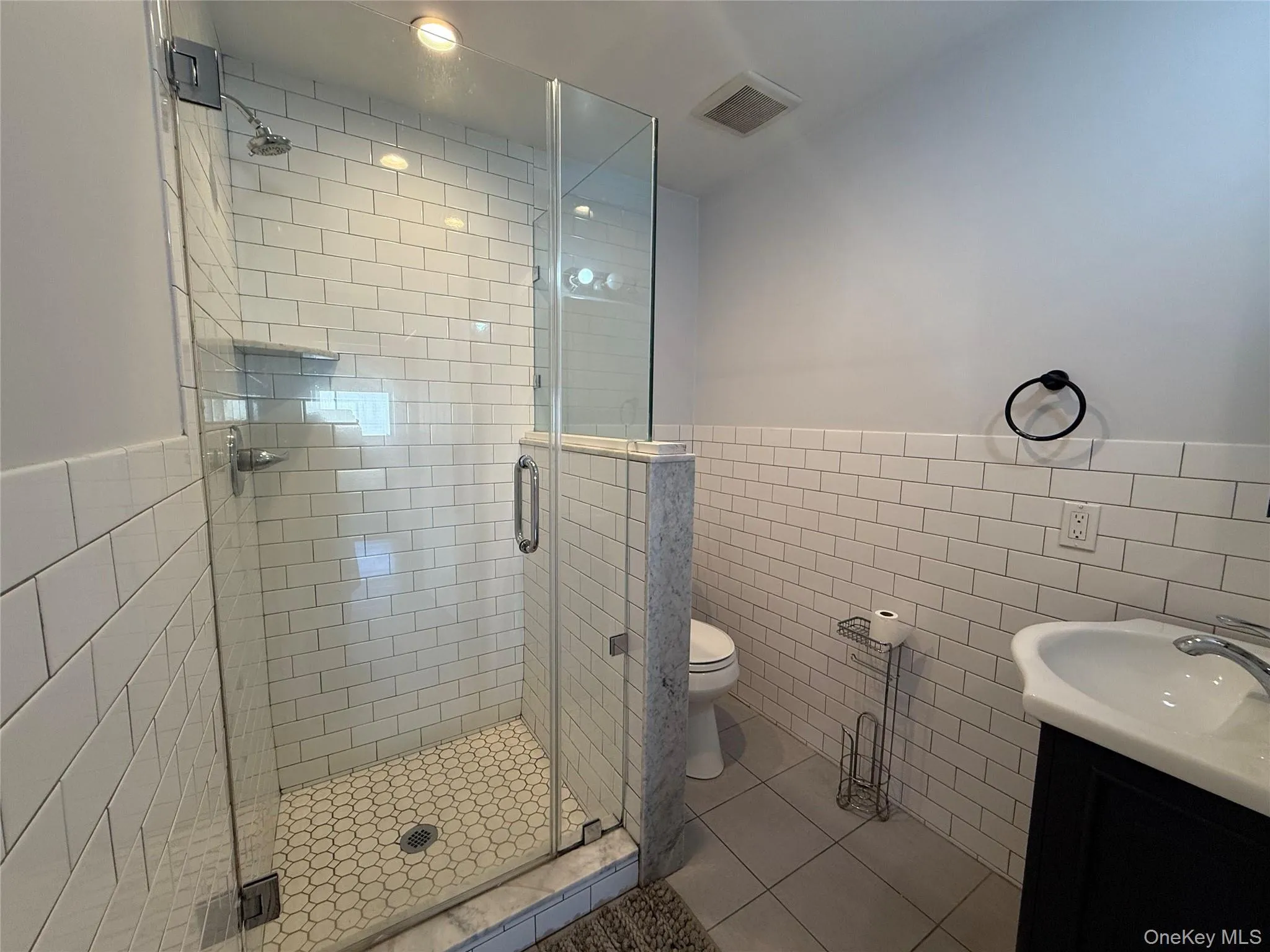 Full bathroom featuring tile walls, tile patterned floors, vanity, and a shower stall Full bathroom featuring tile walls, tile patterned floors, vanity, and a shower stall