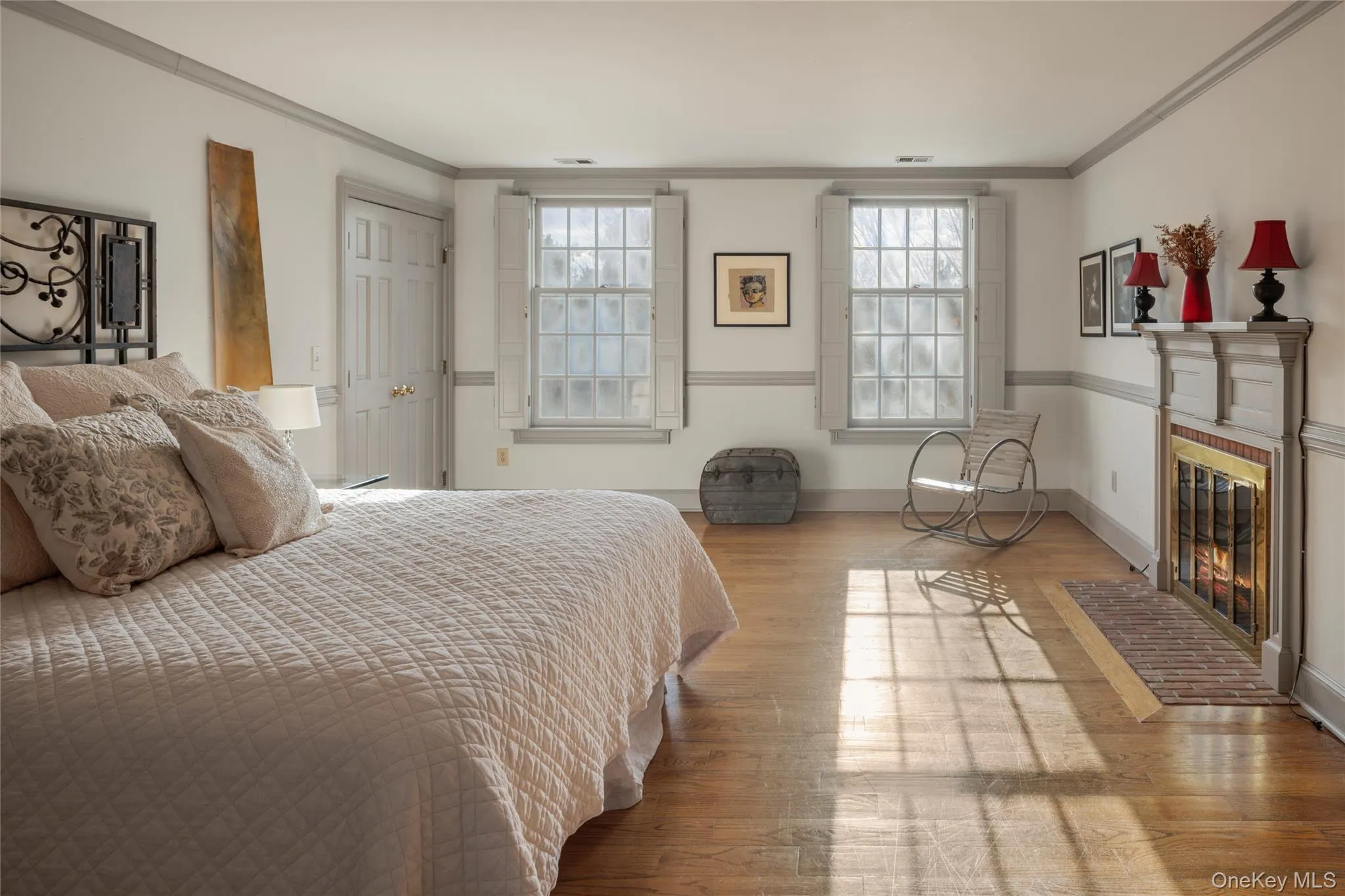 Bedroom featuring wood finished floors, a brick fireplace, baseboards, and ornamental molding Bedroom featuring wood finished floors, a brick fireplace, baseboards, and ornamental molding
