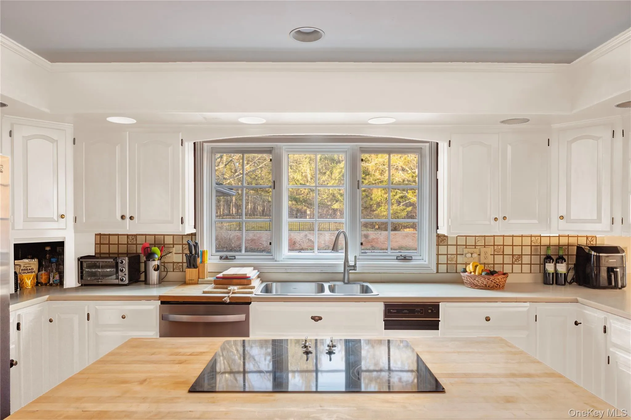 Kitchen featuring white cabinets, black electric stovetop, stainless steel dishwasher, and a sink Kitchen featuring white cabinets, black electric stovetop, stainless steel dishwasher, and a sink