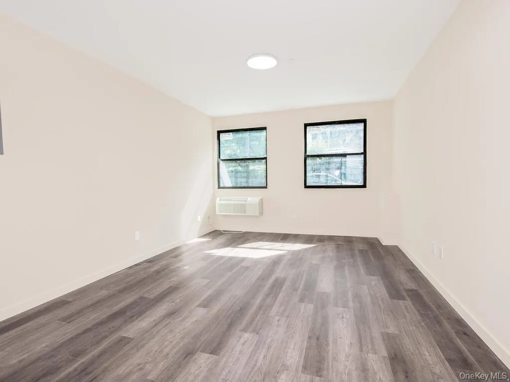Empty room featuring dark wood finished floors and a wall mounted AC Empty room featuring dark wood finished floors and a wall mounted AC