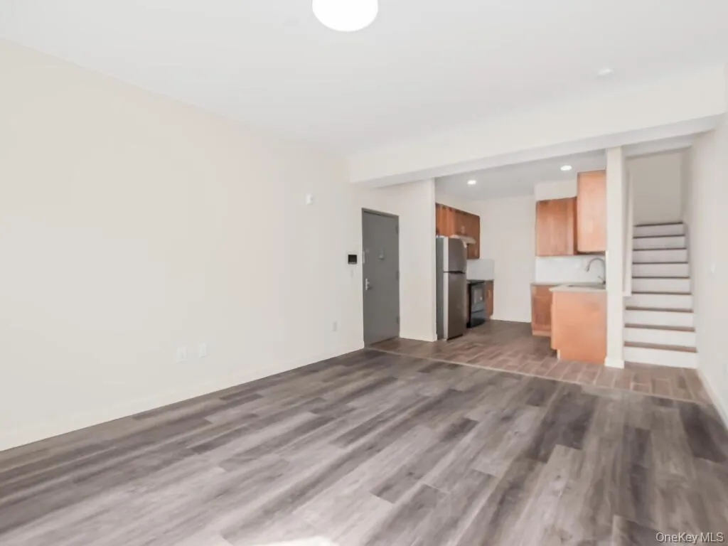 Unfurnished living room with dark wood-type flooring, recessed lighting, and stairway Unfurnished living room with dark wood-type flooring, recessed lighting, and stairway