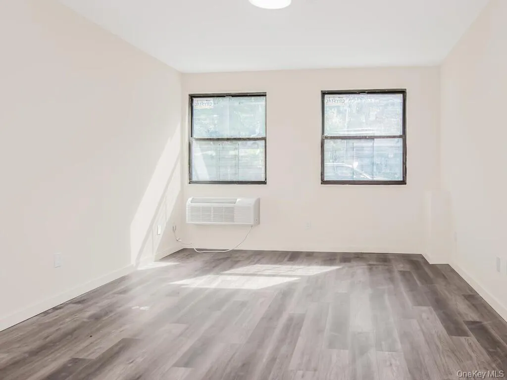 Unfurnished room with light wood-style floors and a wall unit AC Unfurnished room with light wood-style floors and a wall unit AC