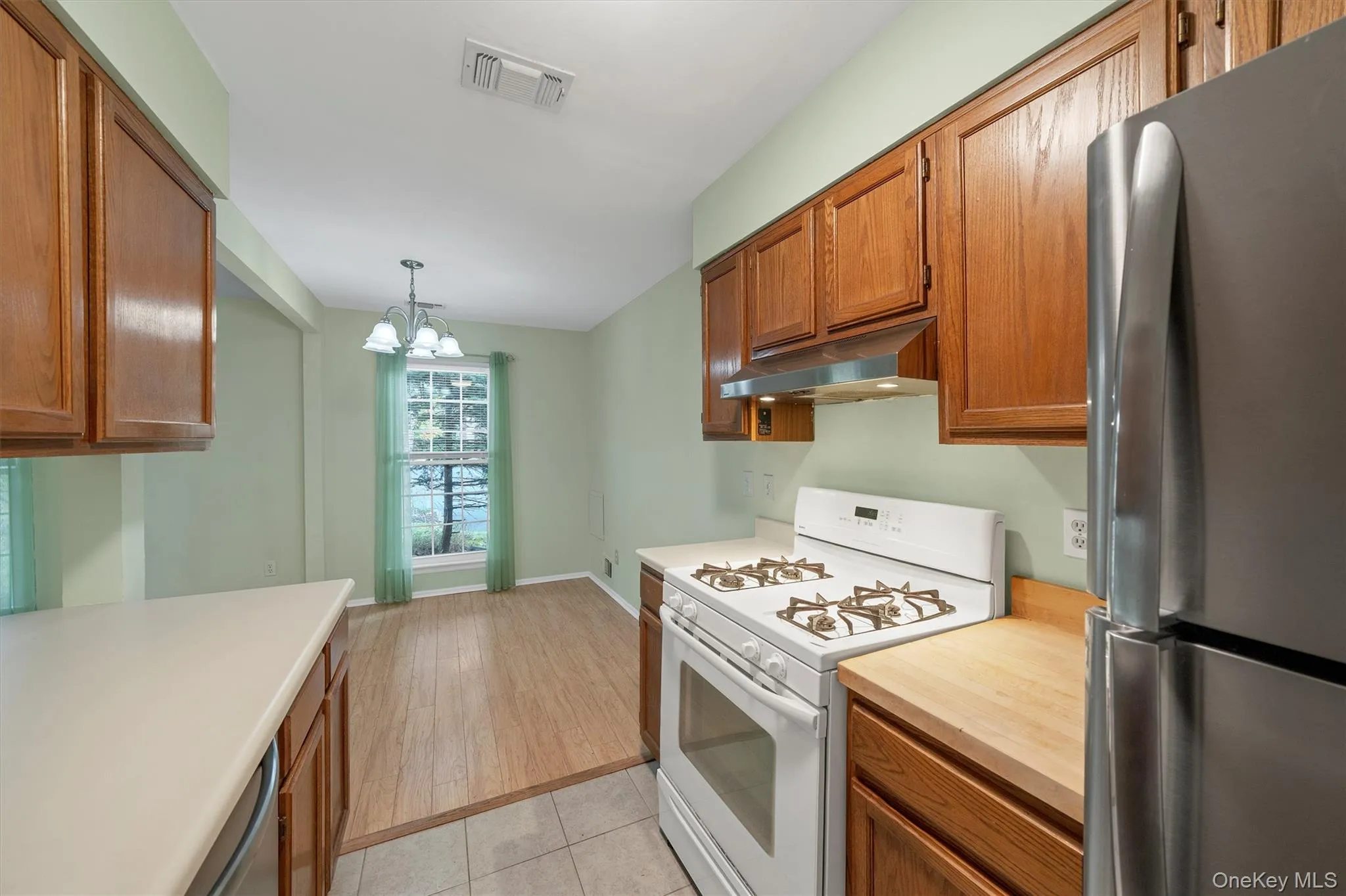 Kitchen with stainless steel appliances, under cabinet range hood, wood cabinets, and light countertops Kitchen with stainless steel appliances, under cabinet range hood, wood cabinets, and light countertops