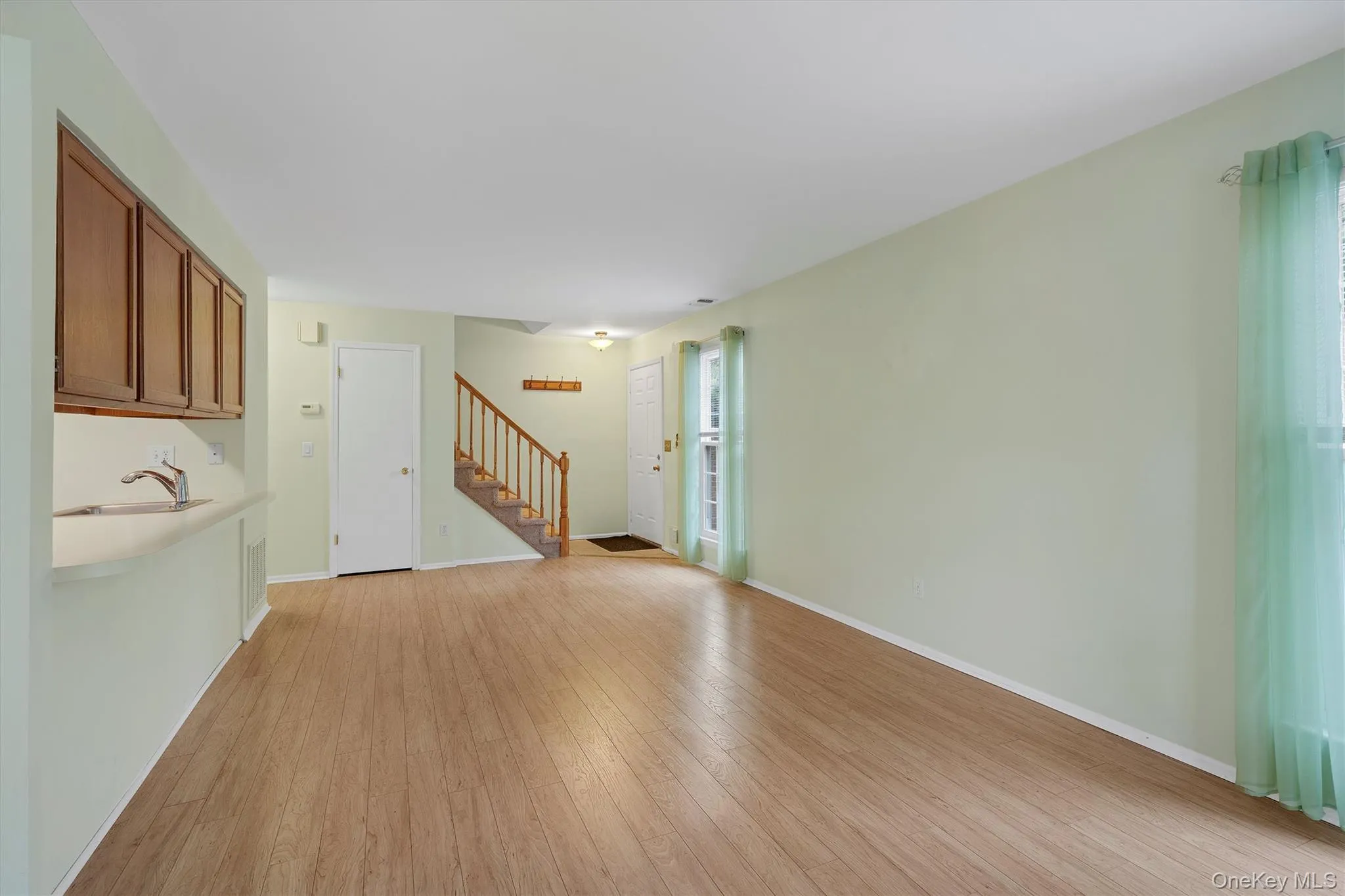 Unfurnished living room featuring light wood-type flooring and stairs Unfurnished living room featuring light wood-type flooring and stairs