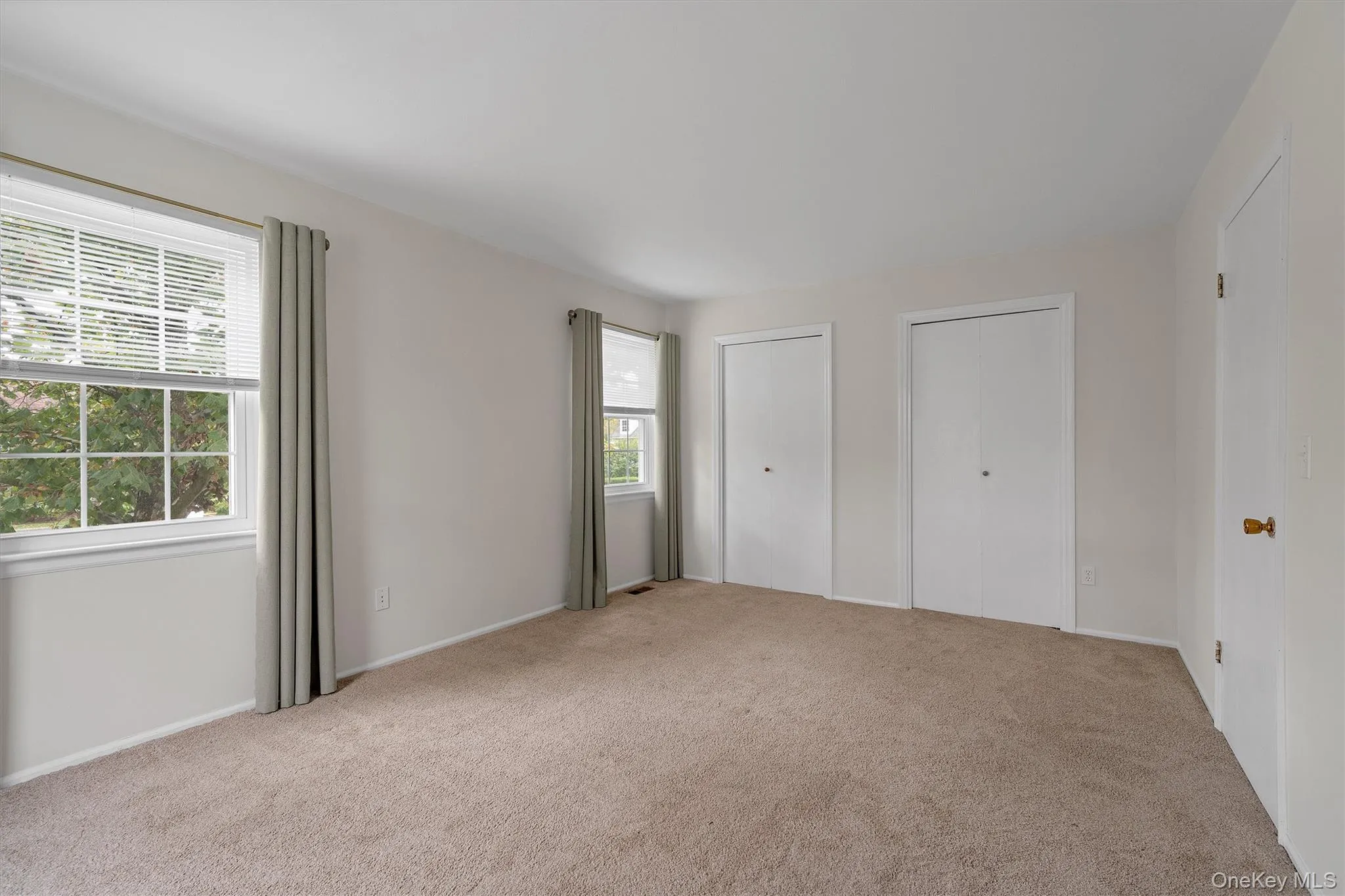 bedroom with multiple closets and light colored carpet bedroom with multiple closets and light colored carpet