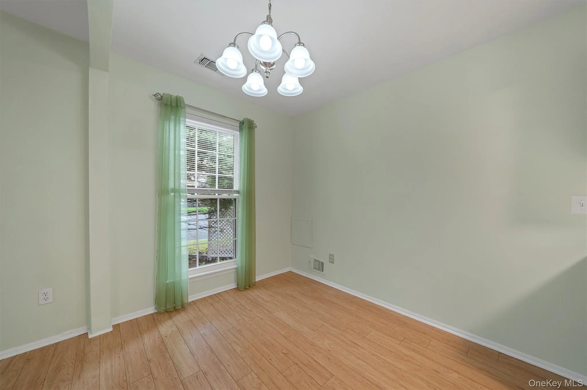 Unfurnished room with a chandelier and light wood finished floors Unfurnished room with a chandelier and light wood finished floors