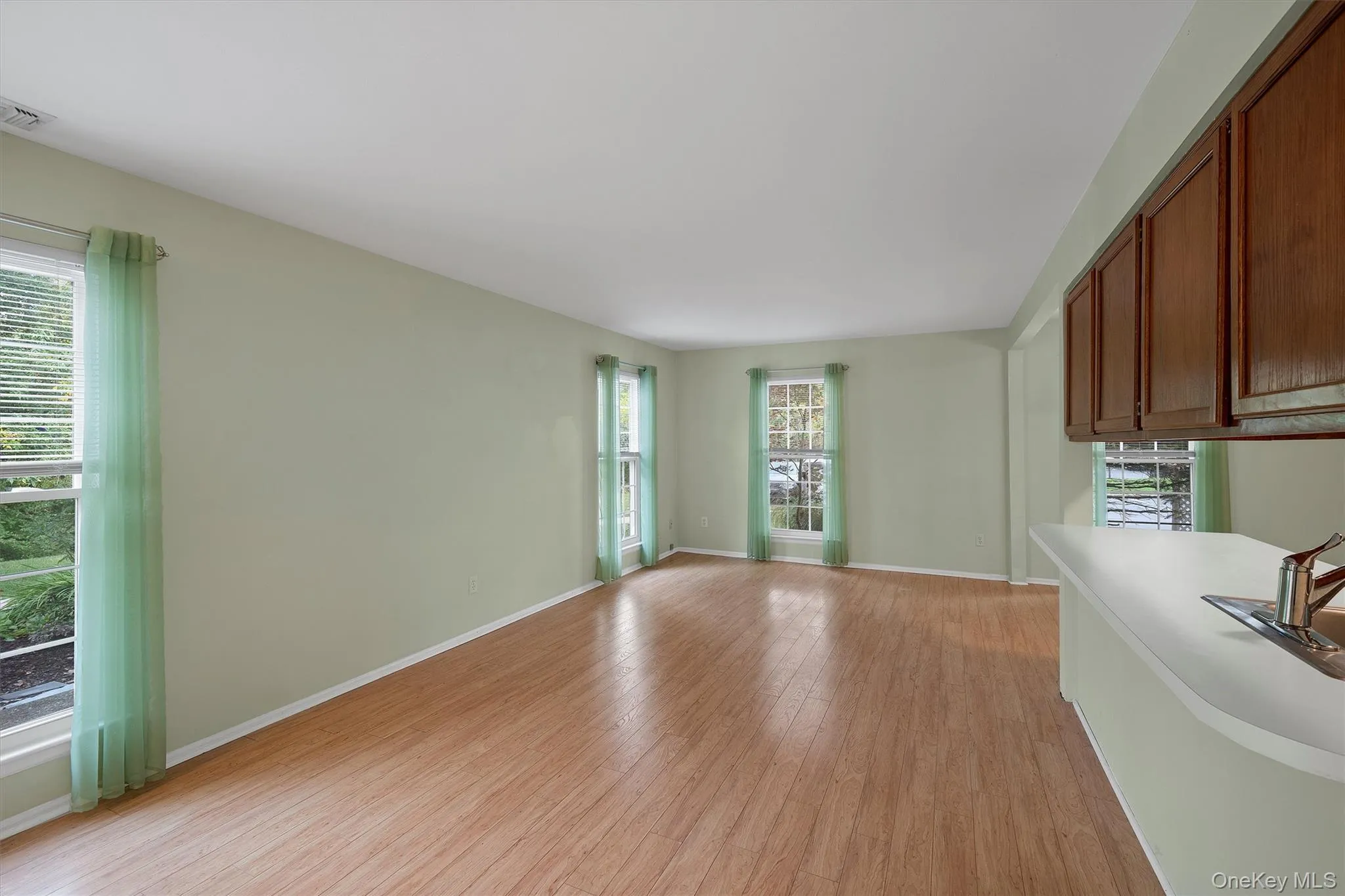Unfurnished living room featuring light wood finished floors and baseboards Unfurnished living room featuring light wood finished floors and baseboards