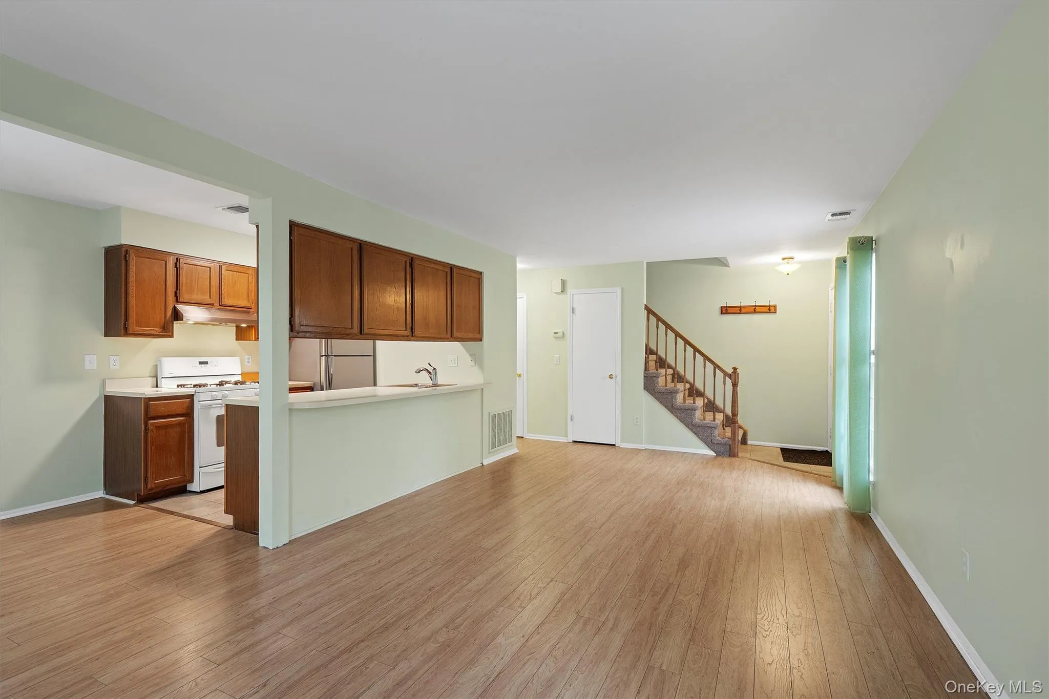 Unfurnished living room featuring light wood-style flooring and stairs Unfurnished living room featuring light wood-style flooring and stairs