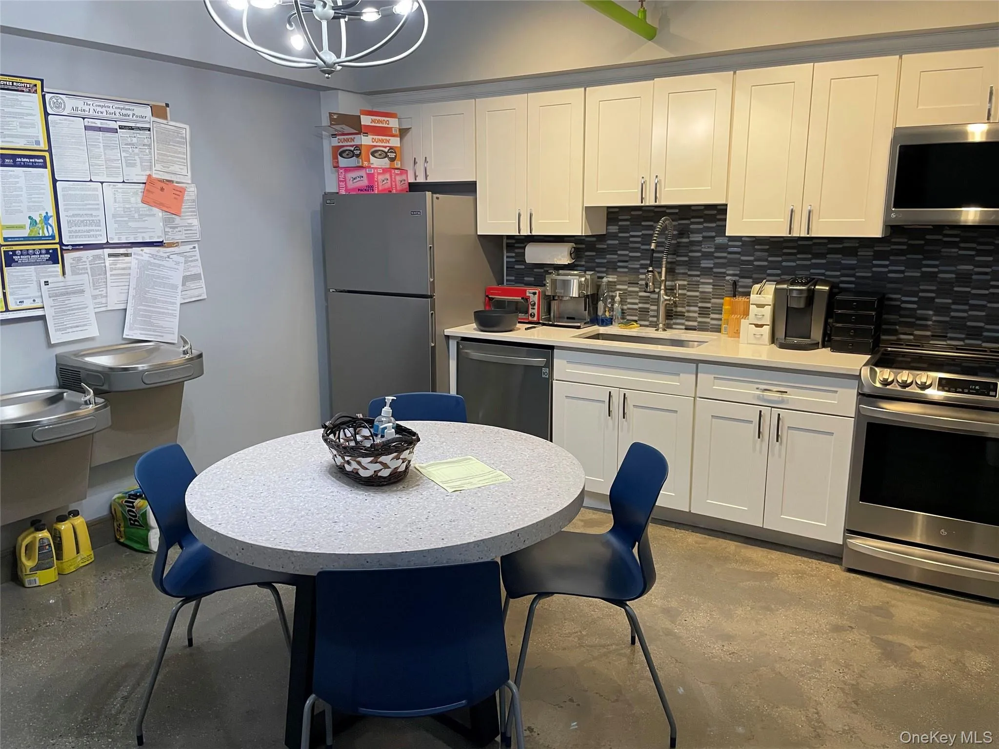 Kitchen featuring concrete floors, appliances with stainless steel finishes, white cabinets, and decorative backsplash Kitchen featuring concrete floors, appliances with stainless steel finishes, white cabinets, and decorative backsplash