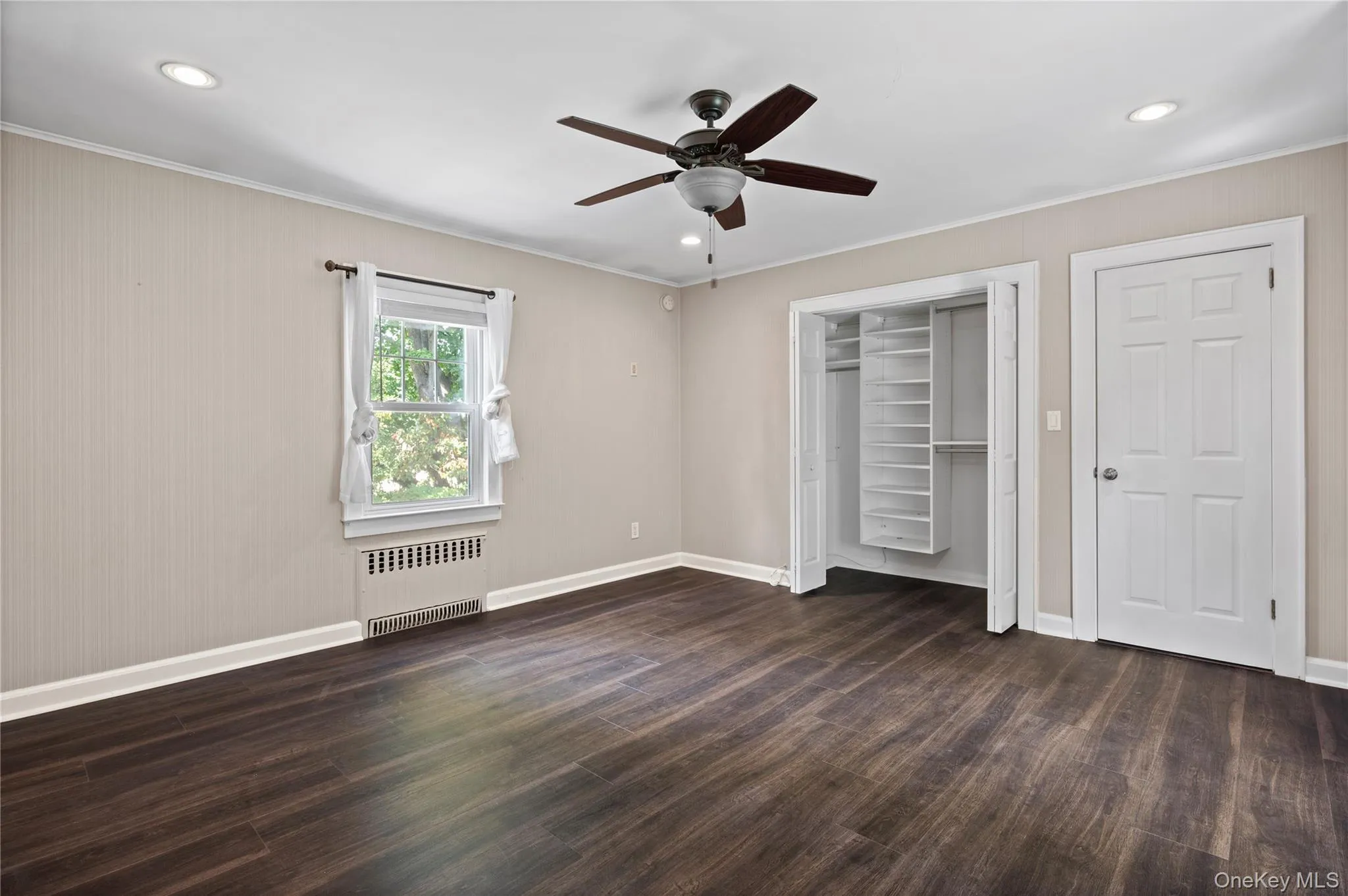 Unfurnished bedroom featuring ornamental molding, radiator heating unit, dark wood-style floors, recessed lighting, and ceiling fan Unfurnished bedroom featuring ornamental molding, radiator heating unit, dark wood-style floors, recessed lighting, and ceiling fan