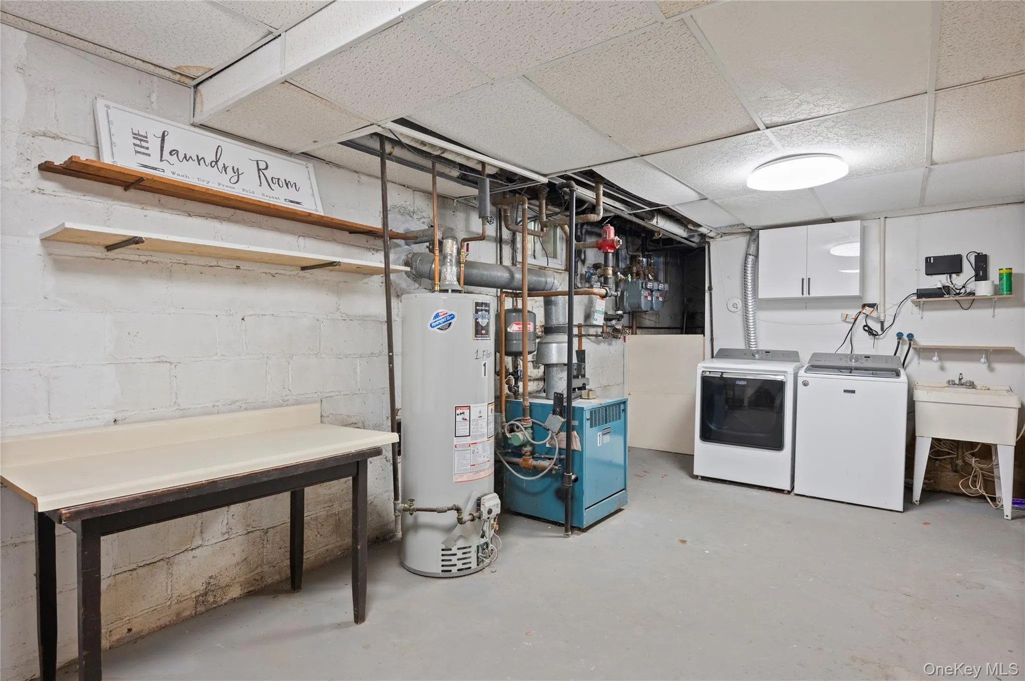 Unfinished below grade area featuring water heater, a paneled ceiling, and independent washer and dryer Unfinished below grade area featuring water heater, a paneled ceiling, and independent washer and dryer
