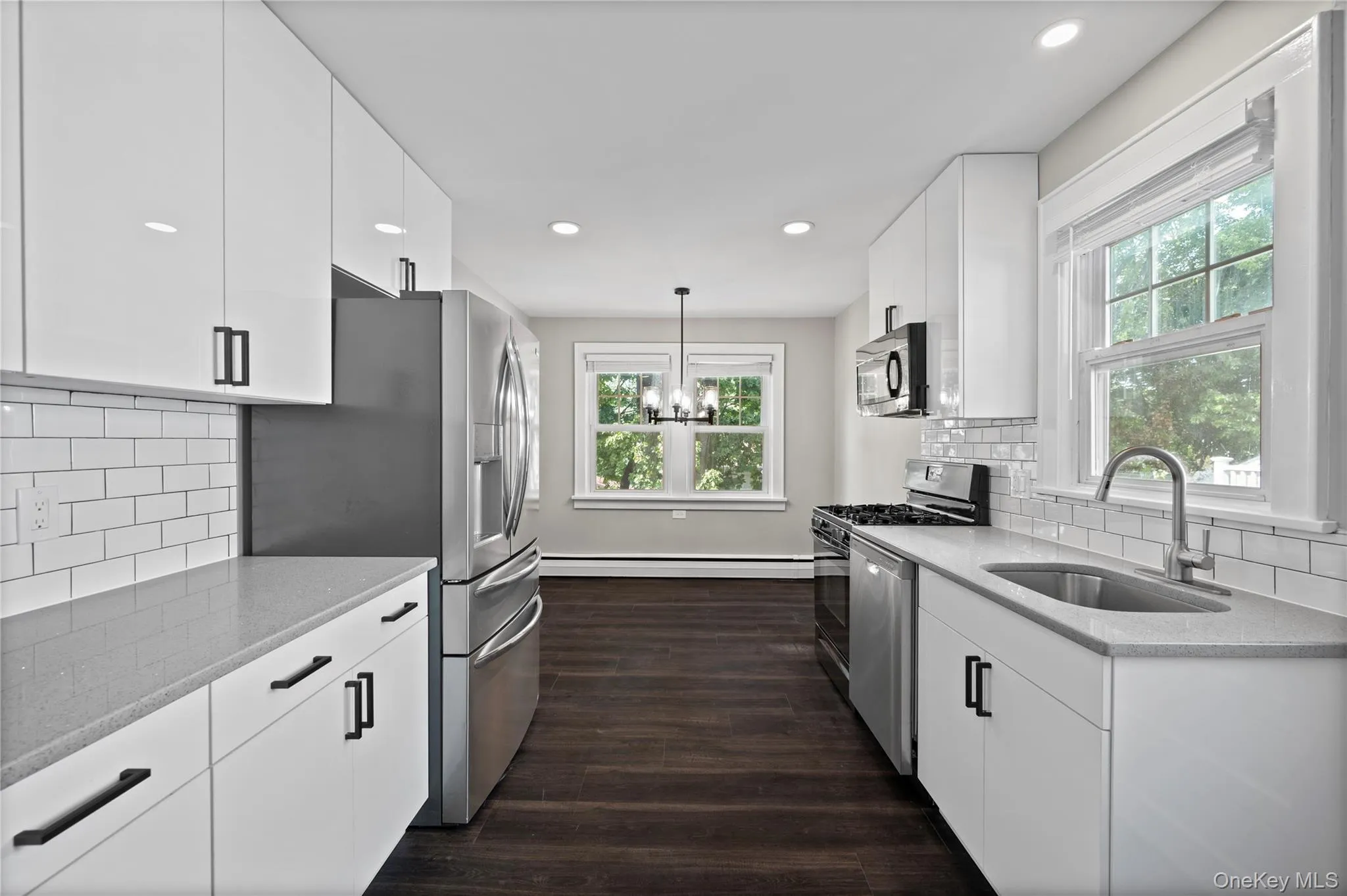 Kitchen with decorative backsplash, white cabinets, light stone countertops, dark wood-style floors, and recessed lighting Kitchen with decorative backsplash, white cabinets, light stone countertops, dark wood-style floors, and recessed lighting