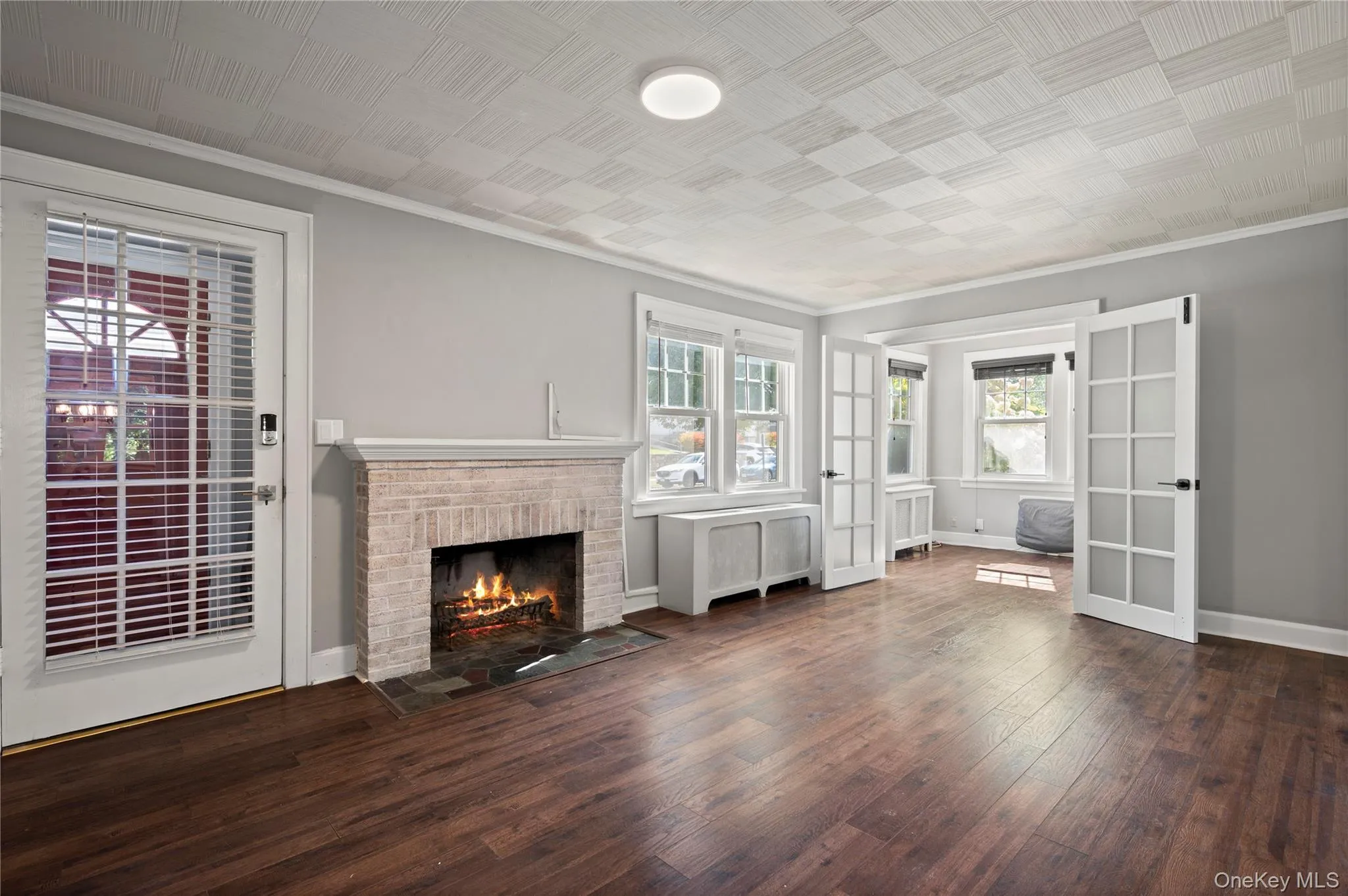 Unfurnished living room featuring dark wood-style floors, a fireplace, ornamental molding, and radiator Unfurnished living room featuring dark wood-style floors, a fireplace, ornamental molding, and radiator