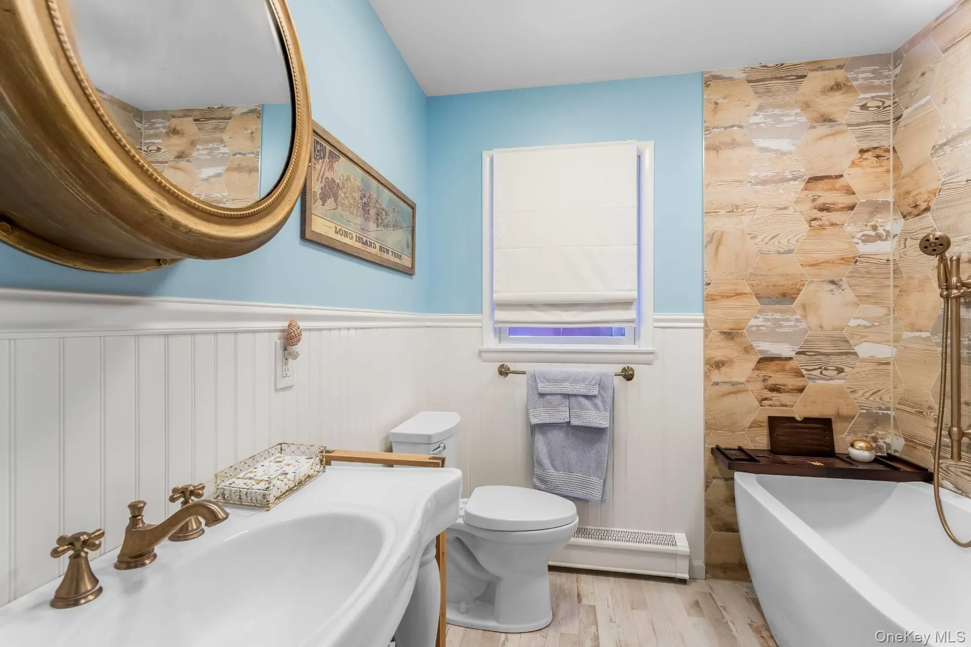 Bathroom with a freestanding tub, light wood-style floors, baseboard heating, and a wainscoted wall Bathroom with a freestanding tub, light wood-style floors, baseboard heating, and a wainscoted wall