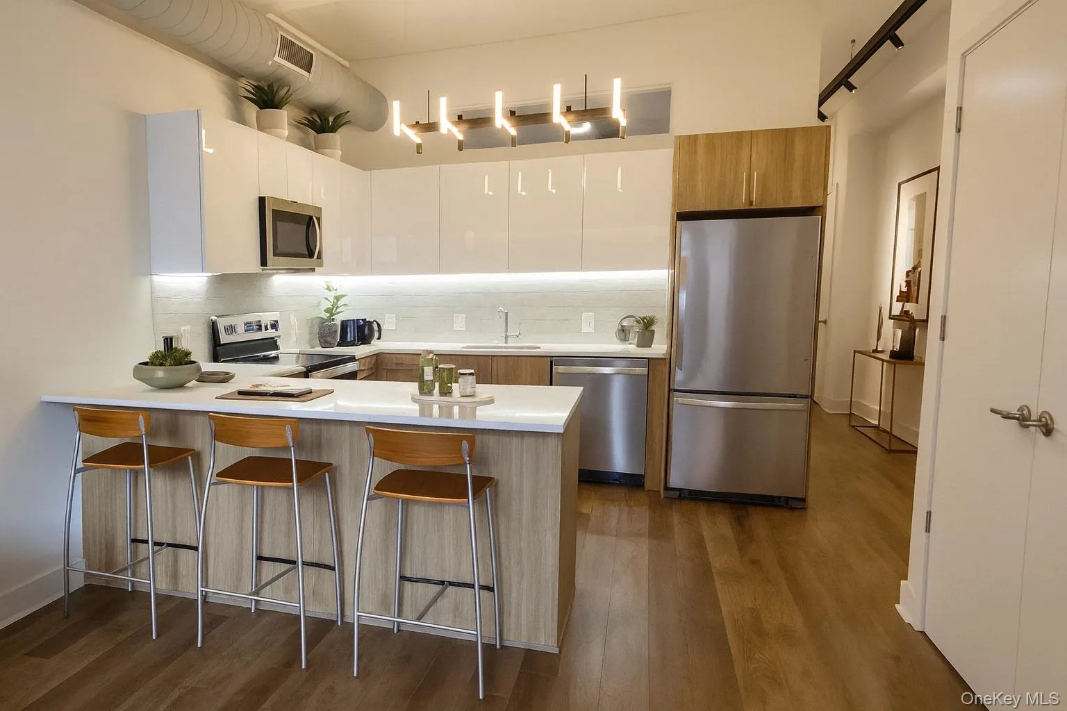 Kitchen with tasteful backsplash, a peninsula, appliances with stainless steel finishes, a kitchen breakfast bar, and modern cabinets Kitchen with tasteful backsplash, a peninsula, appliances with stainless steel finishes, a kitchen breakfast bar, and modern cabinets
