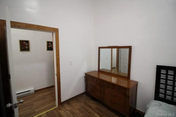 Bedroom with dark wood-style floors and baseboard heating Bedroom with dark wood-style floors and baseboard heating