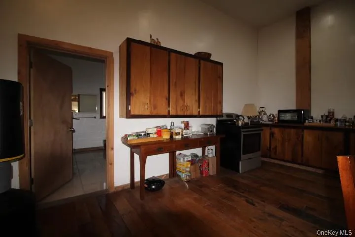 Kitchen with stainless steel electric stove, dark wood-style flooring, and brown cabinets Kitchen with stainless steel electric stove, dark wood-style flooring, and brown cabinets