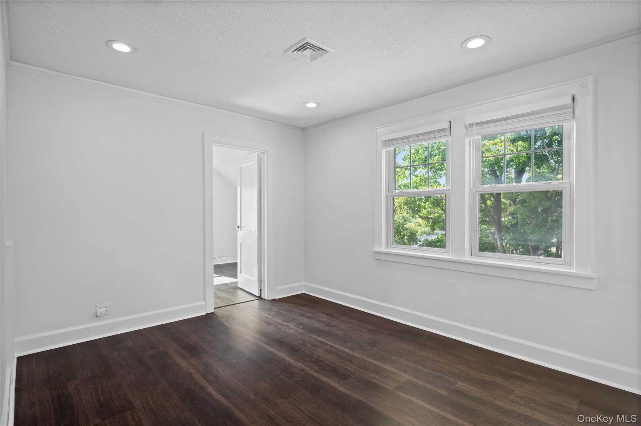 Unfurnished room with dark wood-style floors, crown molding, recessed lighting, and a textured ceiling Unfurnished room with dark wood-style floors, crown molding, recessed lighting, and a textured ceiling