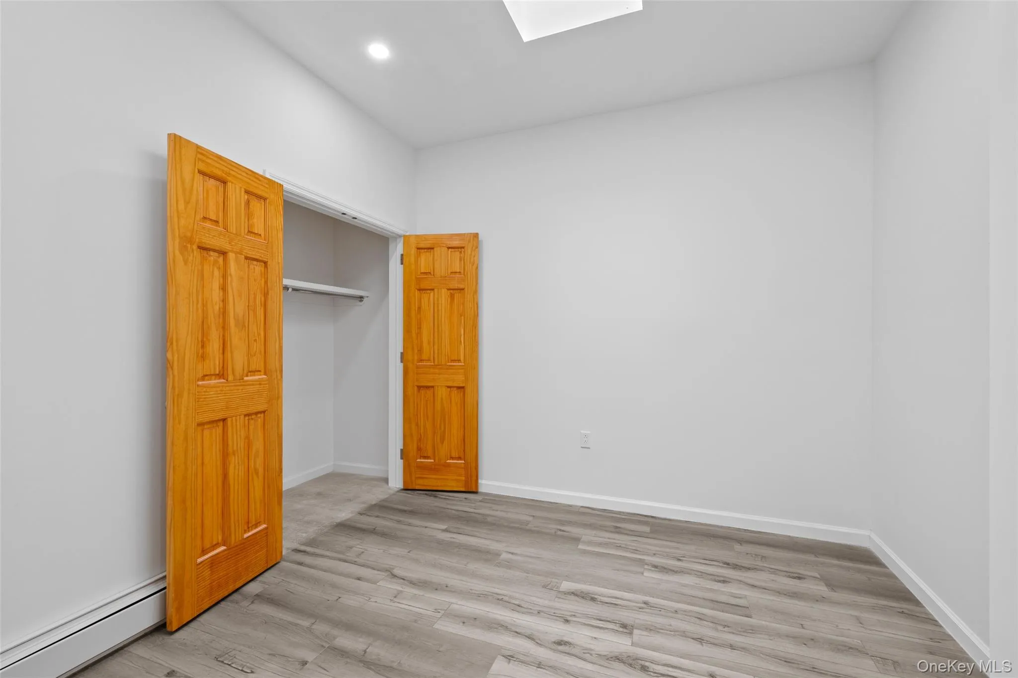 Unfurnished bedroom featuring a baseboard radiator, light wood-type flooring, a skylight, and recessed lighting Unfurnished bedroom featuring a baseboard radiator, light wood-type flooring, a skylight, and recessed lighting