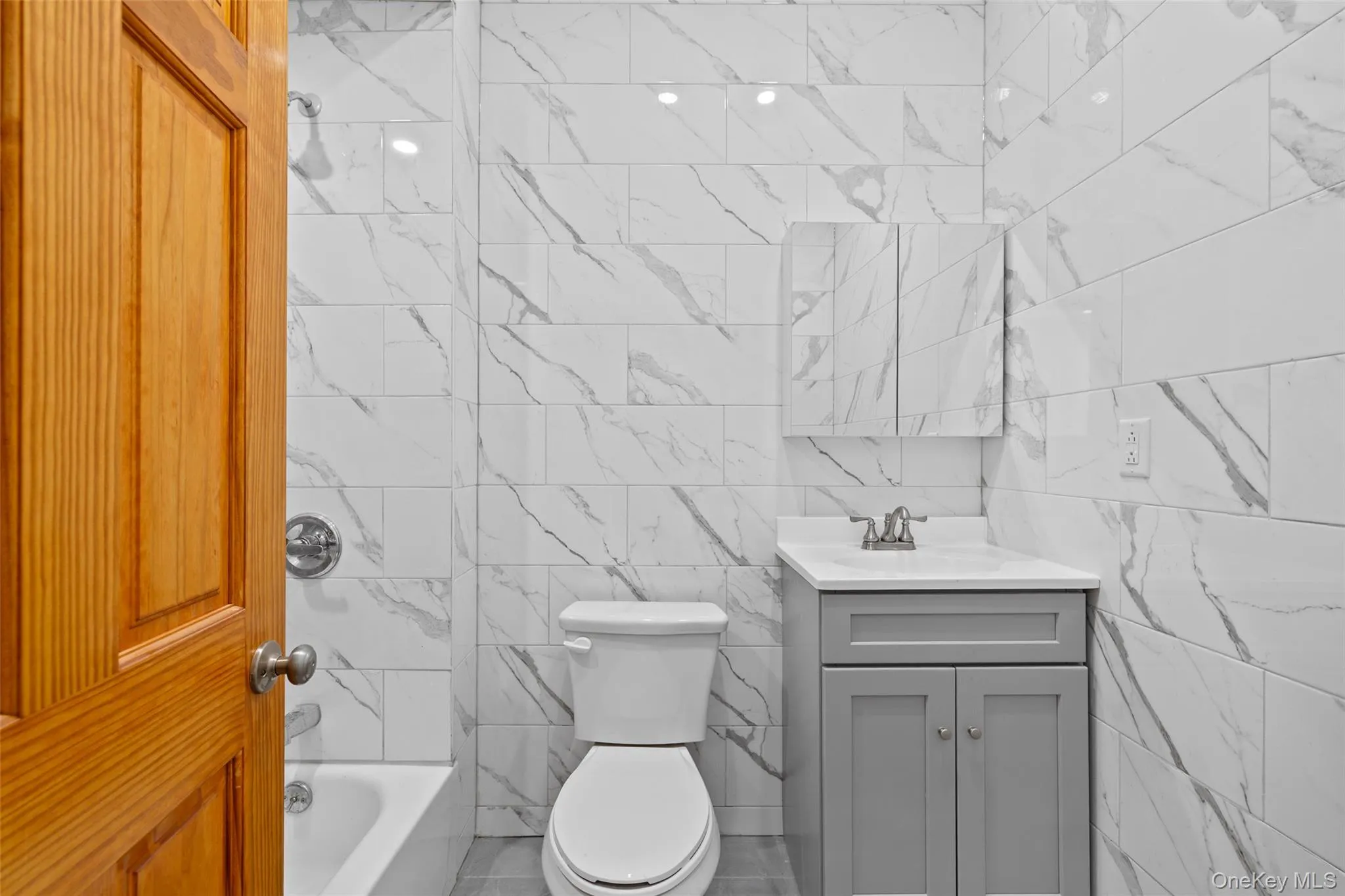 Bathroom with vanity, bathing tub / shower combination, and tile walls Bathroom with vanity, bathing tub / shower combination, and tile walls