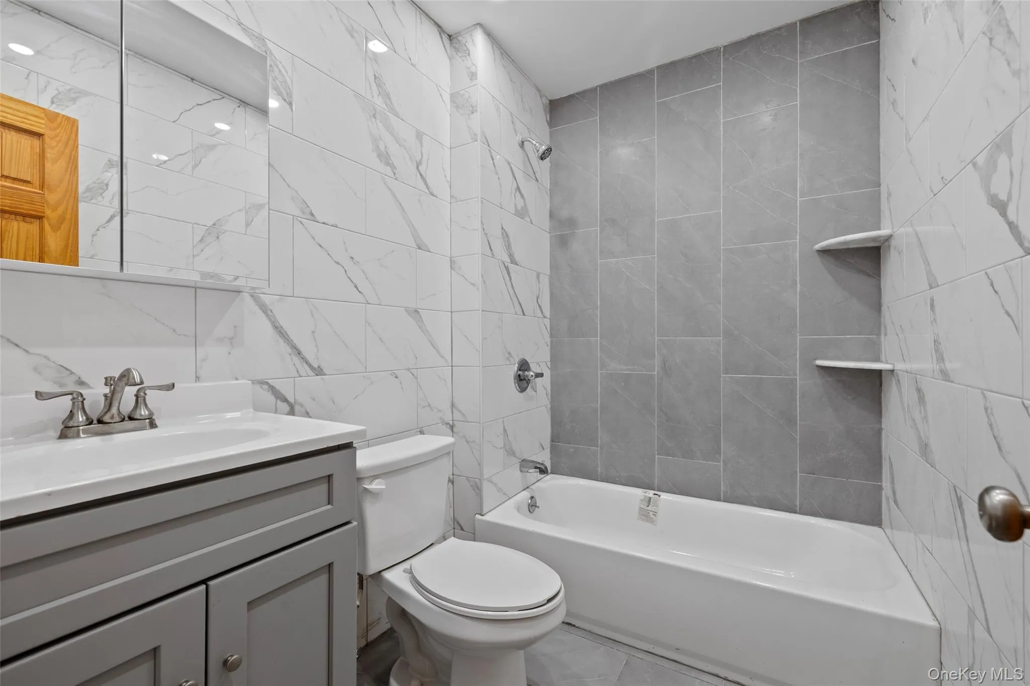 Full bathroom with tile walls, shower / bath combination, and vanity Full bathroom with tile walls, shower / bath combination, and vanity