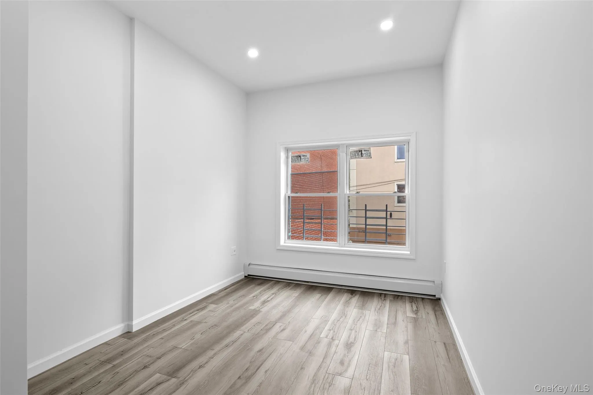 Unfurnished room featuring a baseboard heating unit, light wood-style flooring, and recessed lighting Unfurnished room featuring a baseboard heating unit, light wood-style flooring, and recessed lighting