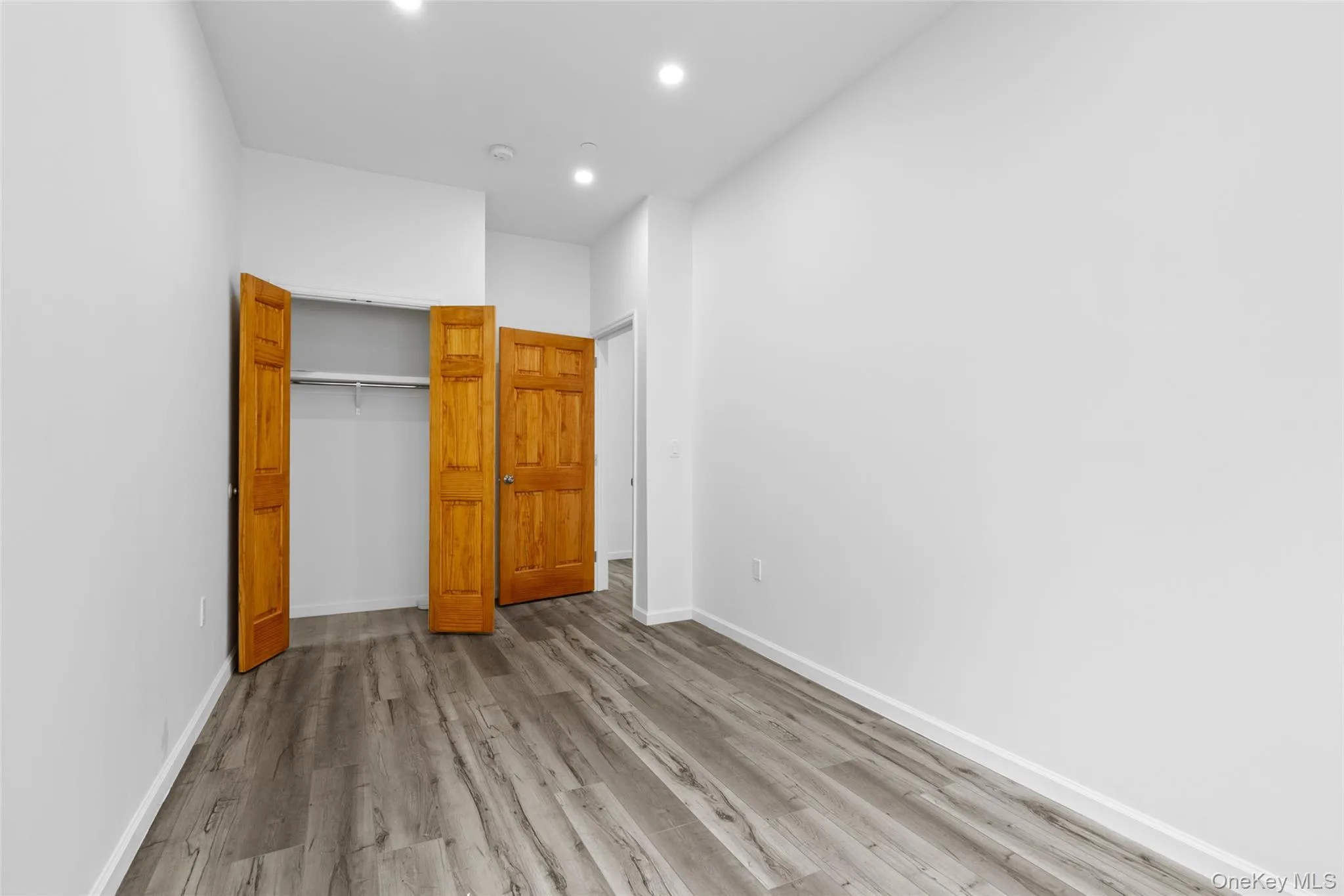 Unfurnished bedroom with wood finished floors, a closet, and recessed lighting Unfurnished bedroom with wood finished floors, a closet, and recessed lighting