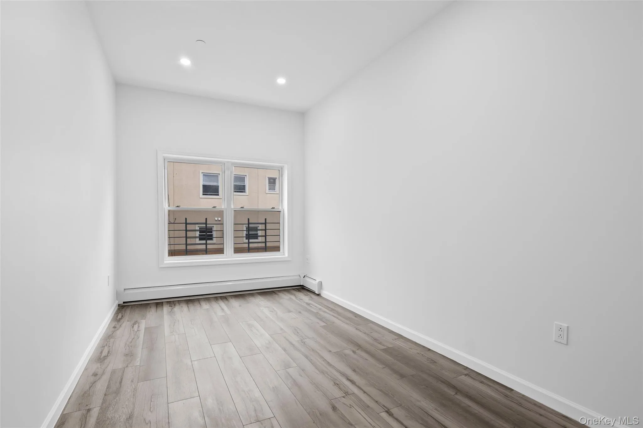 Empty room featuring light wood-type flooring, a baseboard heating unit, and recessed lighting Empty room featuring light wood-type flooring, a baseboard heating unit, and recessed lighting