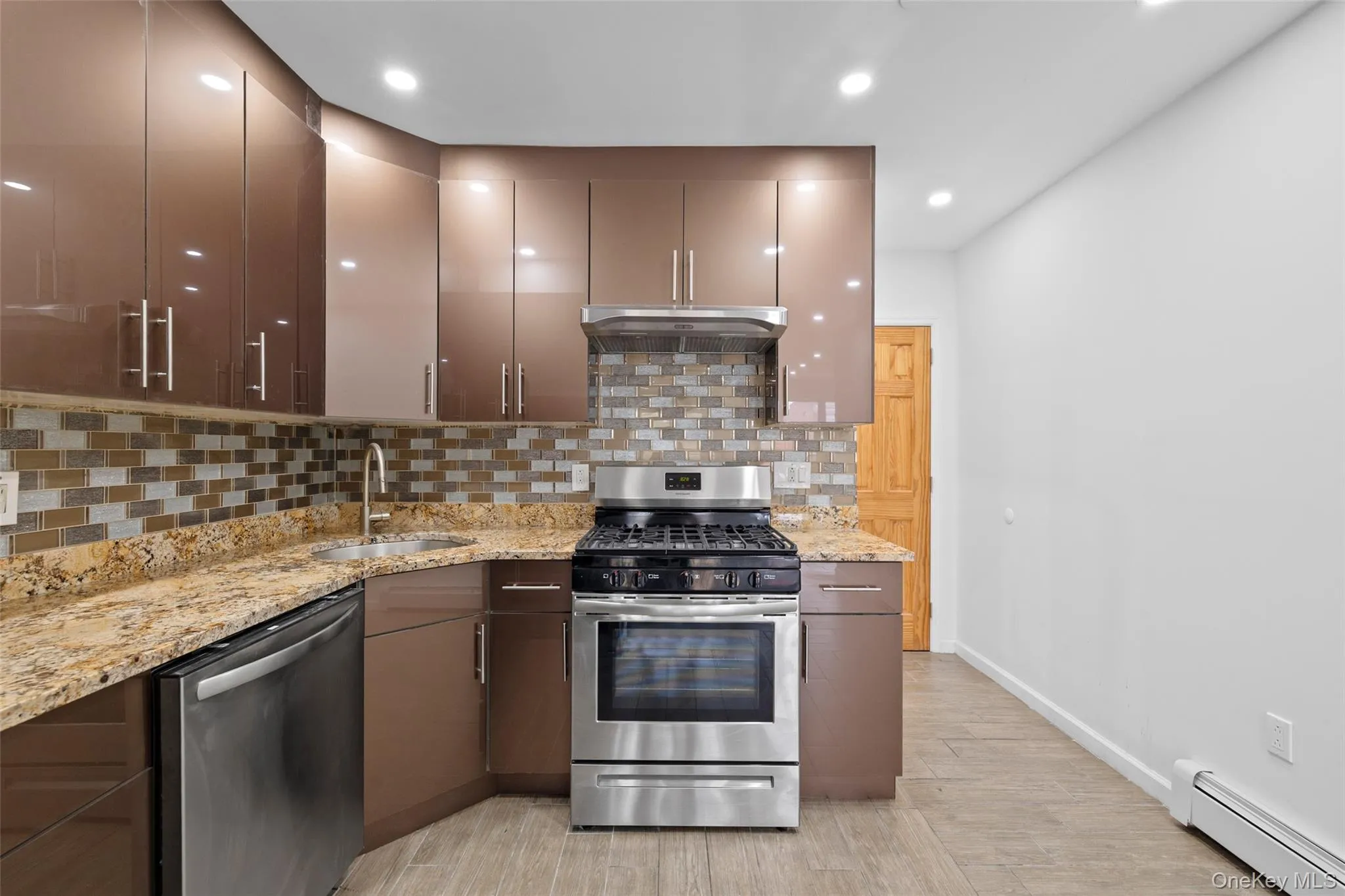 Kitchen with stainless steel appliances, a baseboard heating unit, tasteful backsplash, light stone counters, and recessed lighting Kitchen with stainless steel appliances, a baseboard heating unit, tasteful backsplash, light stone counters, and recessed lighting