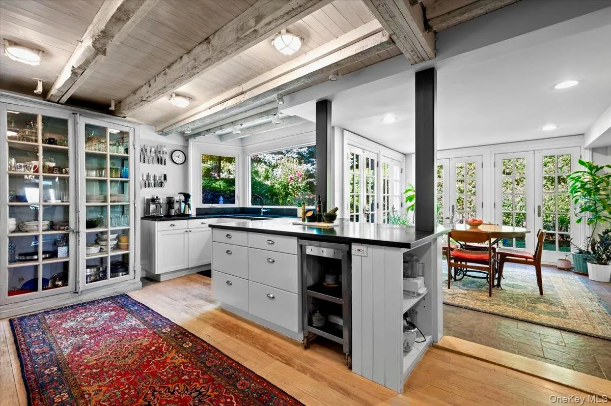 Kitchen featuring eat in area, open shelves, dark countertops, light wood-style floors, beam ceiling, and white cabinets Kitchen featuring eat in area, open shelves, dark countertops, light wood-style floors, beam ceiling, and white cabinets