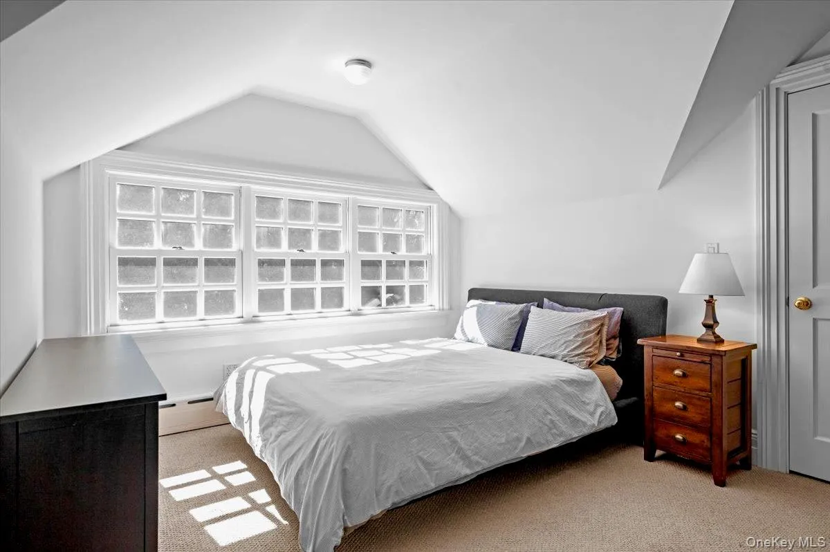 Carpeted bedroom featuring a baseboard heating unit and vaulted ceiling Carpeted bedroom featuring a baseboard heating unit and vaulted ceiling