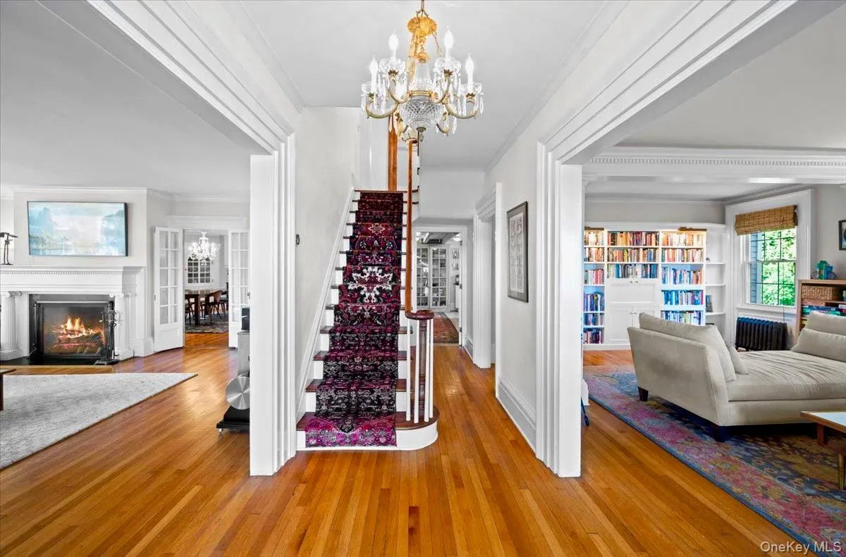 Entrance foyer featuring a chandelier, ornamental molding, hardwood / wood-style floors, stairway, and a fireplace Entrance foyer featuring a chandelier, ornamental molding, hardwood / wood-style floors, stairway, and a fireplace