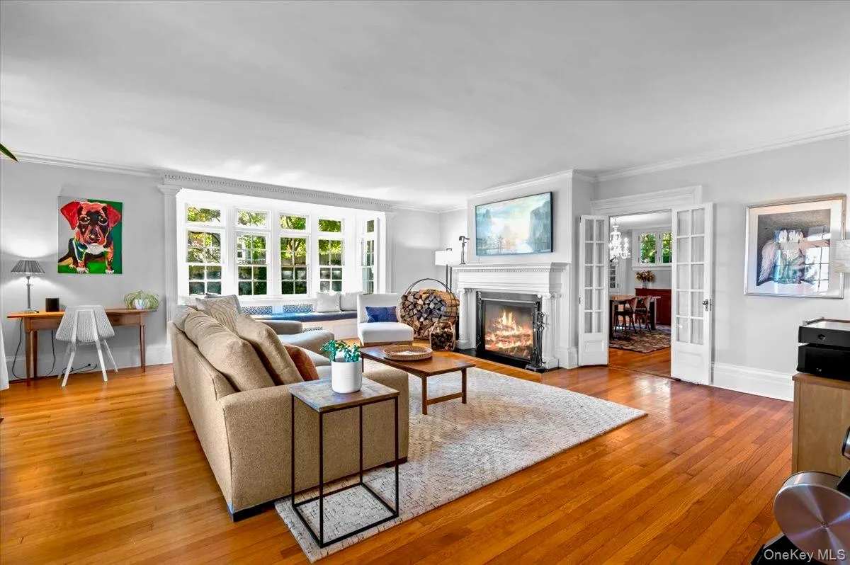 Living area with a fireplace , french doors, light wood-type flooring, and ornamental molding Living area with a fireplace , french doors, light wood-type flooring, and ornamental molding