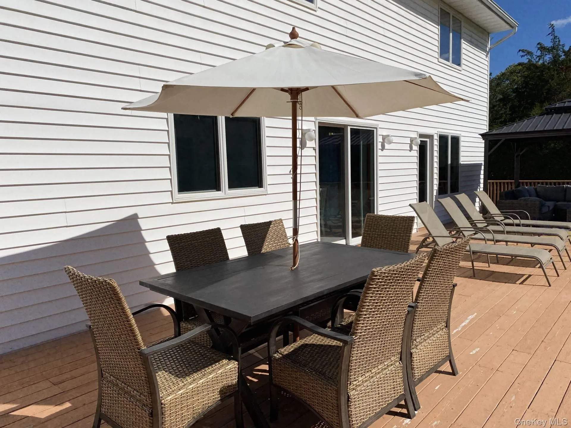 Wooden terrace featuring outdoor dining area and a gazebo Wooden terrace featuring outdoor dining area and a gazebo