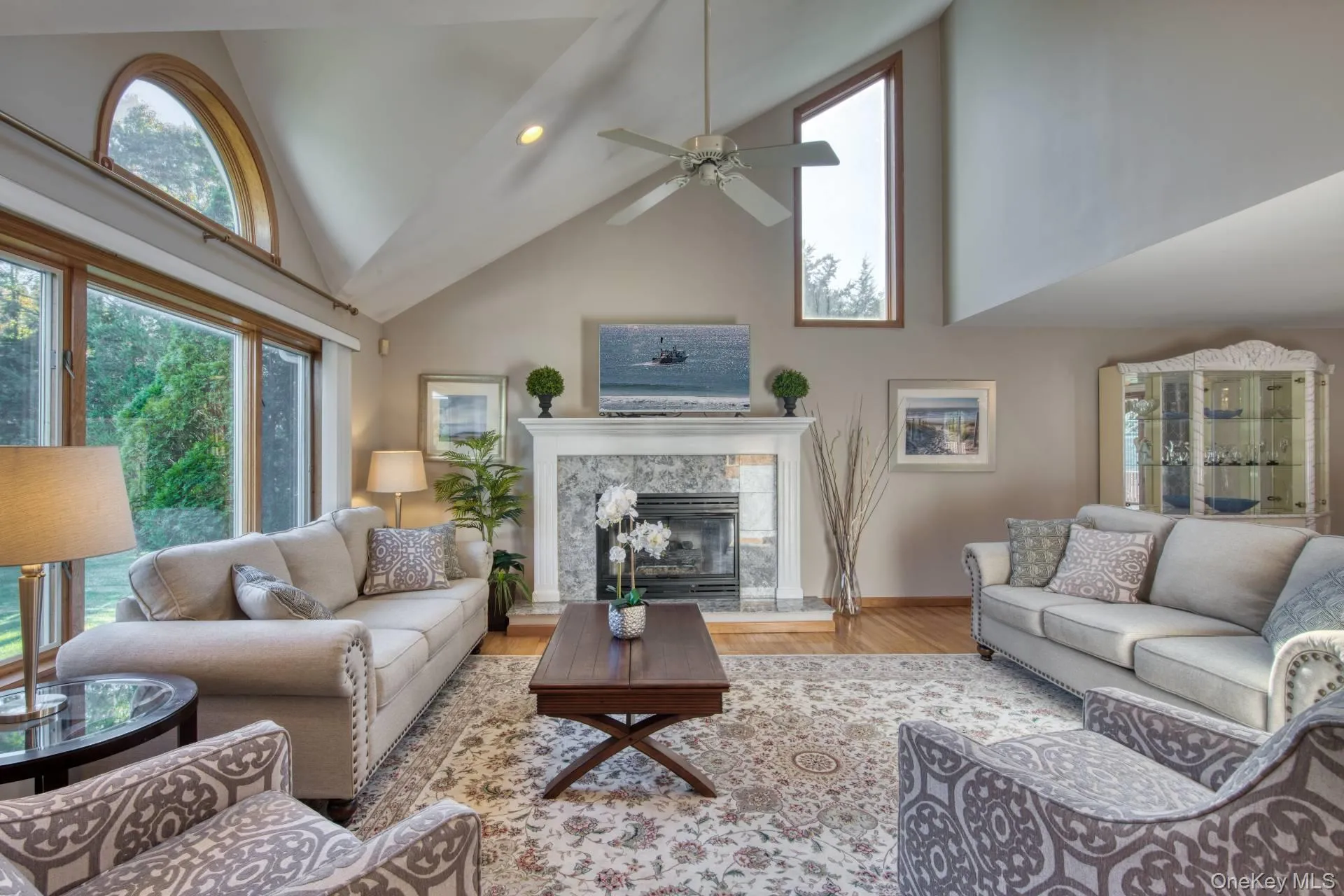 Living room with high vaulted ceiling, wood finished floors, a premium fireplace, recessed lighting, and a ceiling fan Living room with high vaulted ceiling, wood finished floors, a premium fireplace, recessed lighting, and a ceiling fan