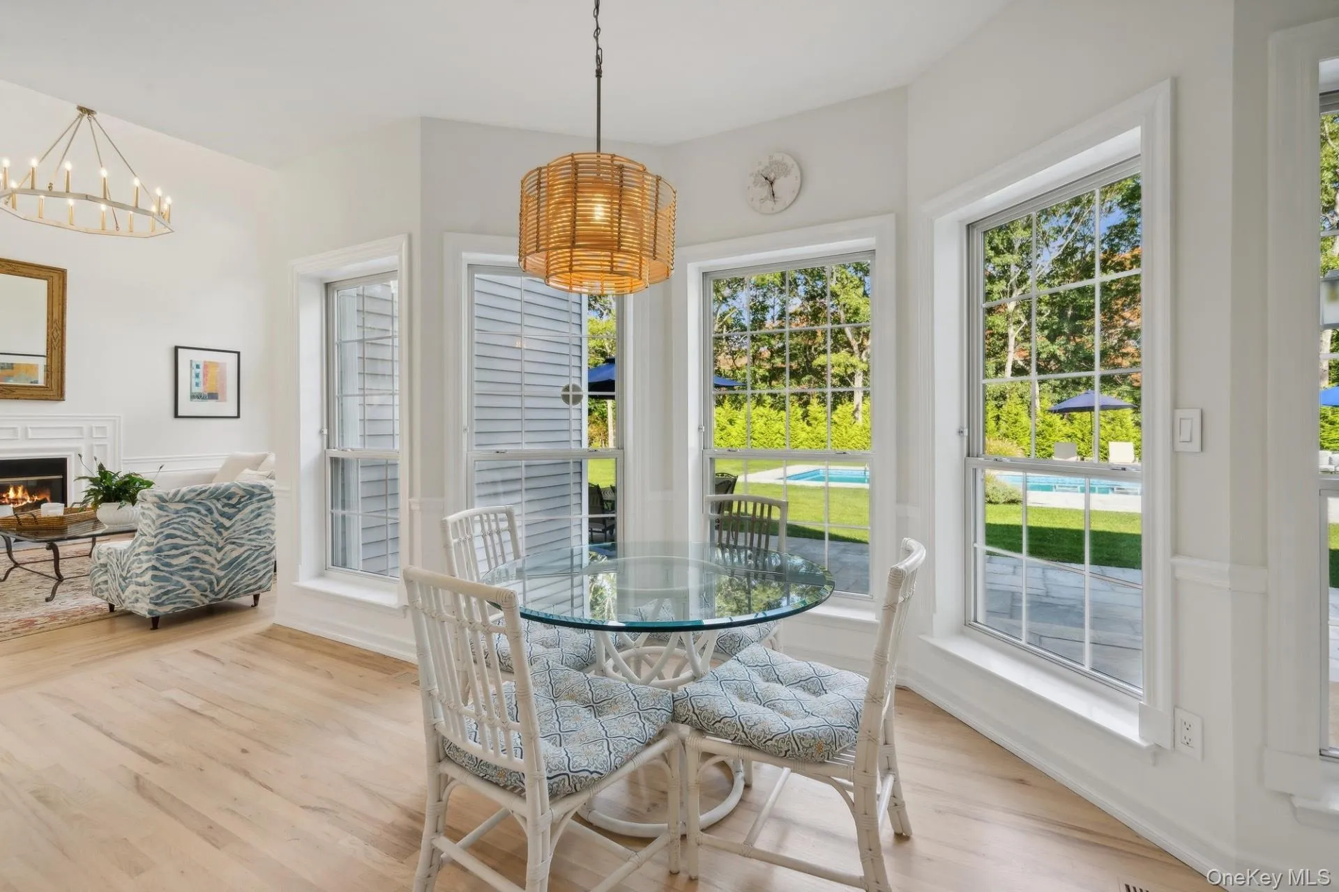 Dining space featuring plenty of natural light, light wood-style flooring, a lit fireplace, and a chandelier Dining space featuring plenty of natural light, light wood-style flooring, a lit fireplace, and a chandelier