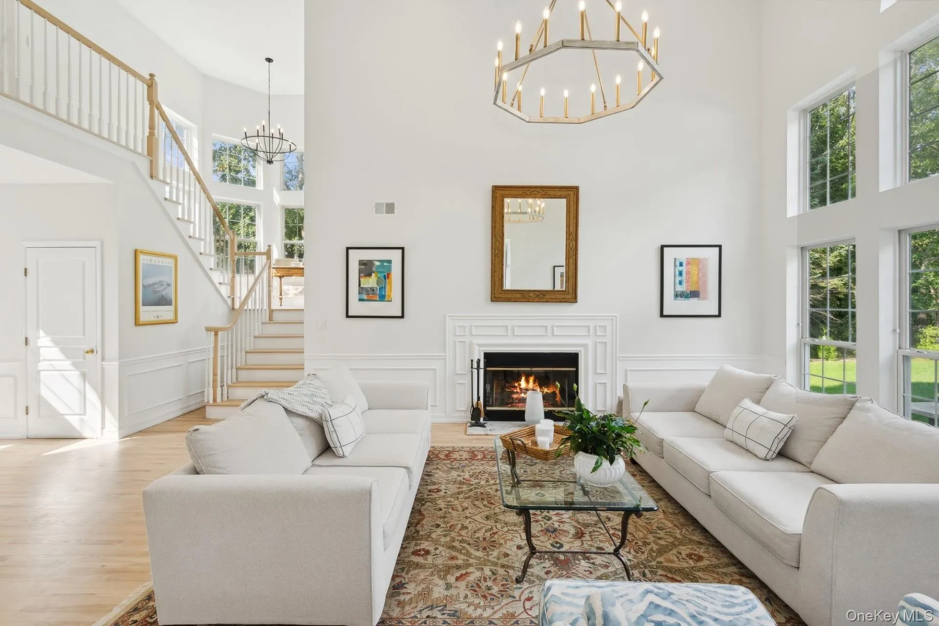 Living area with a decorative wall, wainscoting, a chandelier, a lit fireplace, and a towering ceiling Living area with a decorative wall, wainscoting, a chandelier, a lit fireplace, and a towering ceiling