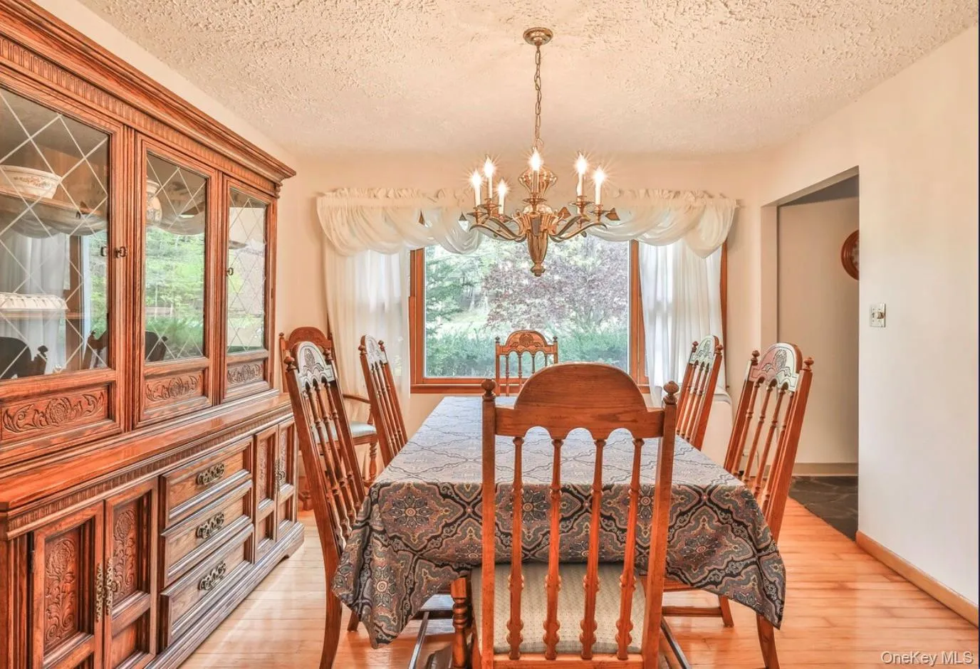 Dining space with light wood-style floors, a chandelier, and a textured ceiling Dining space with light wood-style floors, a chandelier, and a textured ceiling
