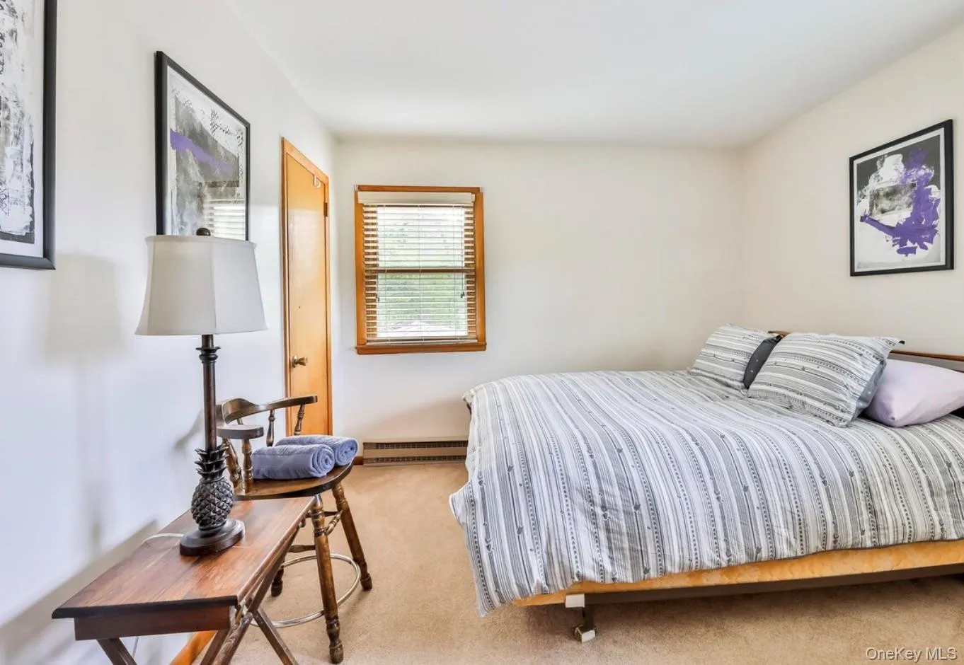 Bedroom featuring light carpet and baseboard heating Bedroom featuring light carpet and baseboard heating