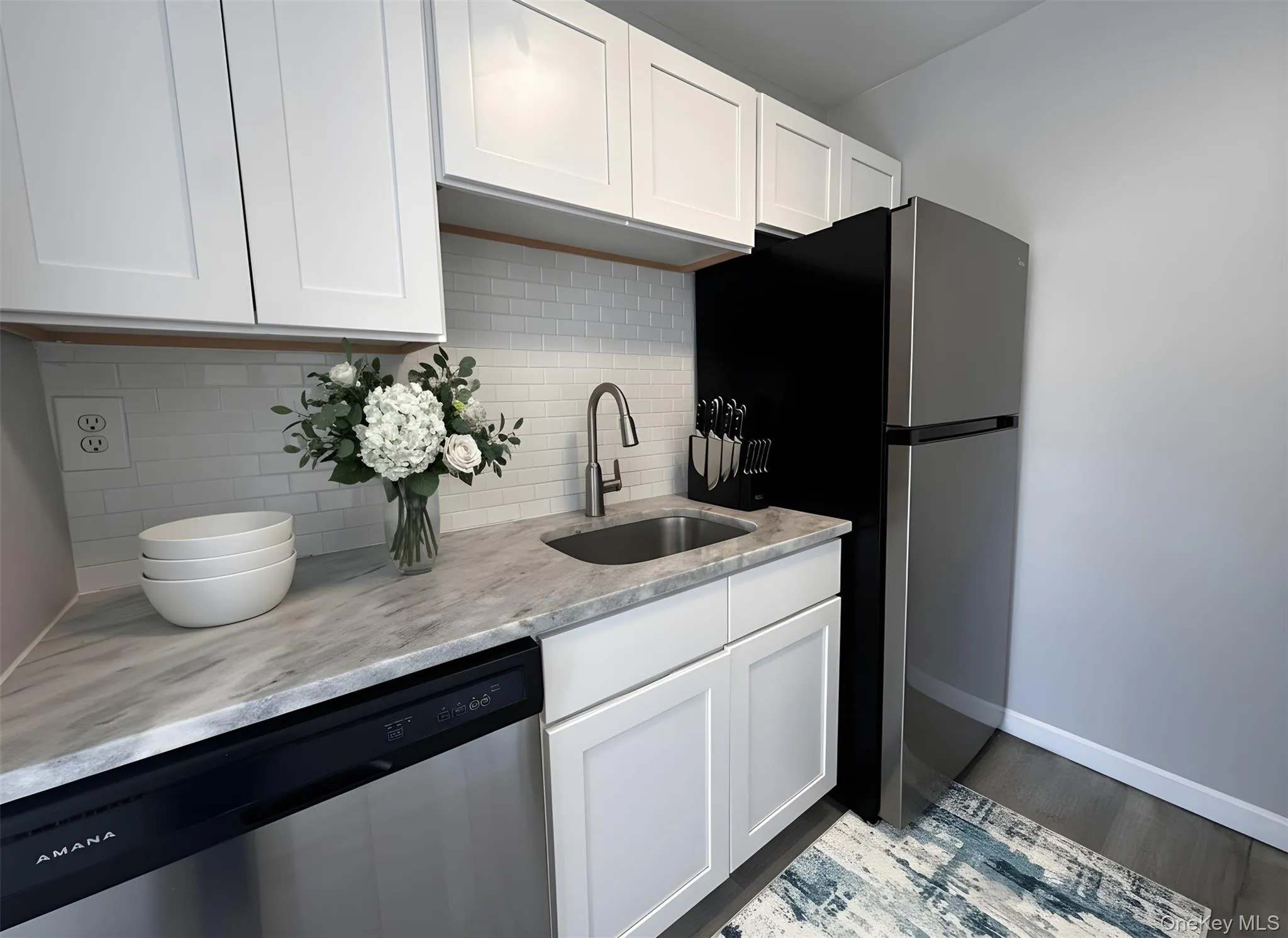 Kitchen featuring stainless steel appliances, backsplash, light stone counters, and white cabinetry Kitchen featuring stainless steel appliances, backsplash, light stone counters, and white cabinetry